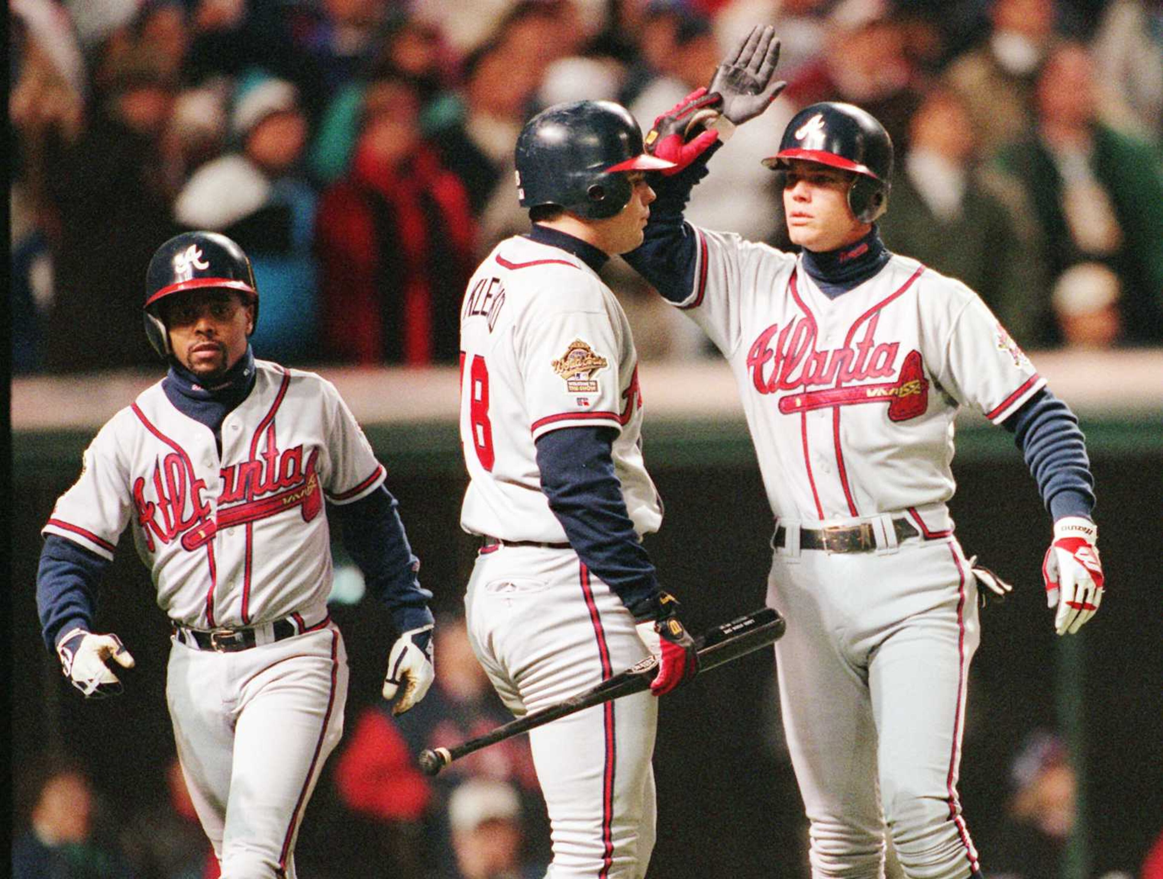 Braves' Ryan Klesko, center, slaps hands with teammate Chipper Jones, right, after Jones scored on a David Justice hit in the seventh inning of Game Four of the World Series at Jacobs Field in Cleveland, Wednesday, Oct. 25, 1995. At left is Luis Polonia who also scored on the play. Klesko hit a home run in the sixth inning.