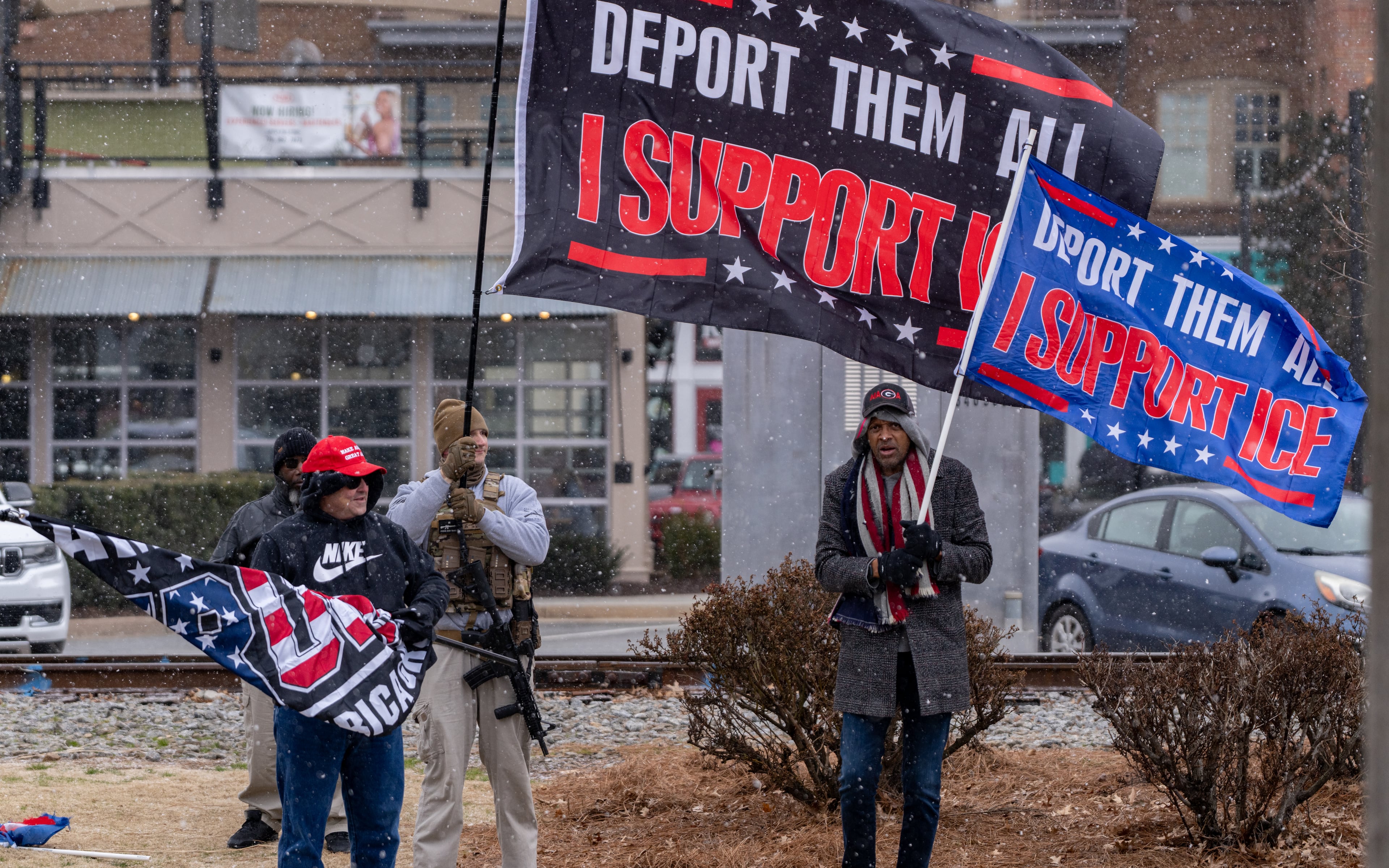 Pro-ICE demonstrators David Sciacca, Brendan, and Vernon Jones wave flags in support of ICE deportations along Main Street in downtown Woodstock, Georgia. Saturday, Jan 31, 2026. (Ben Hendren for the AJC)