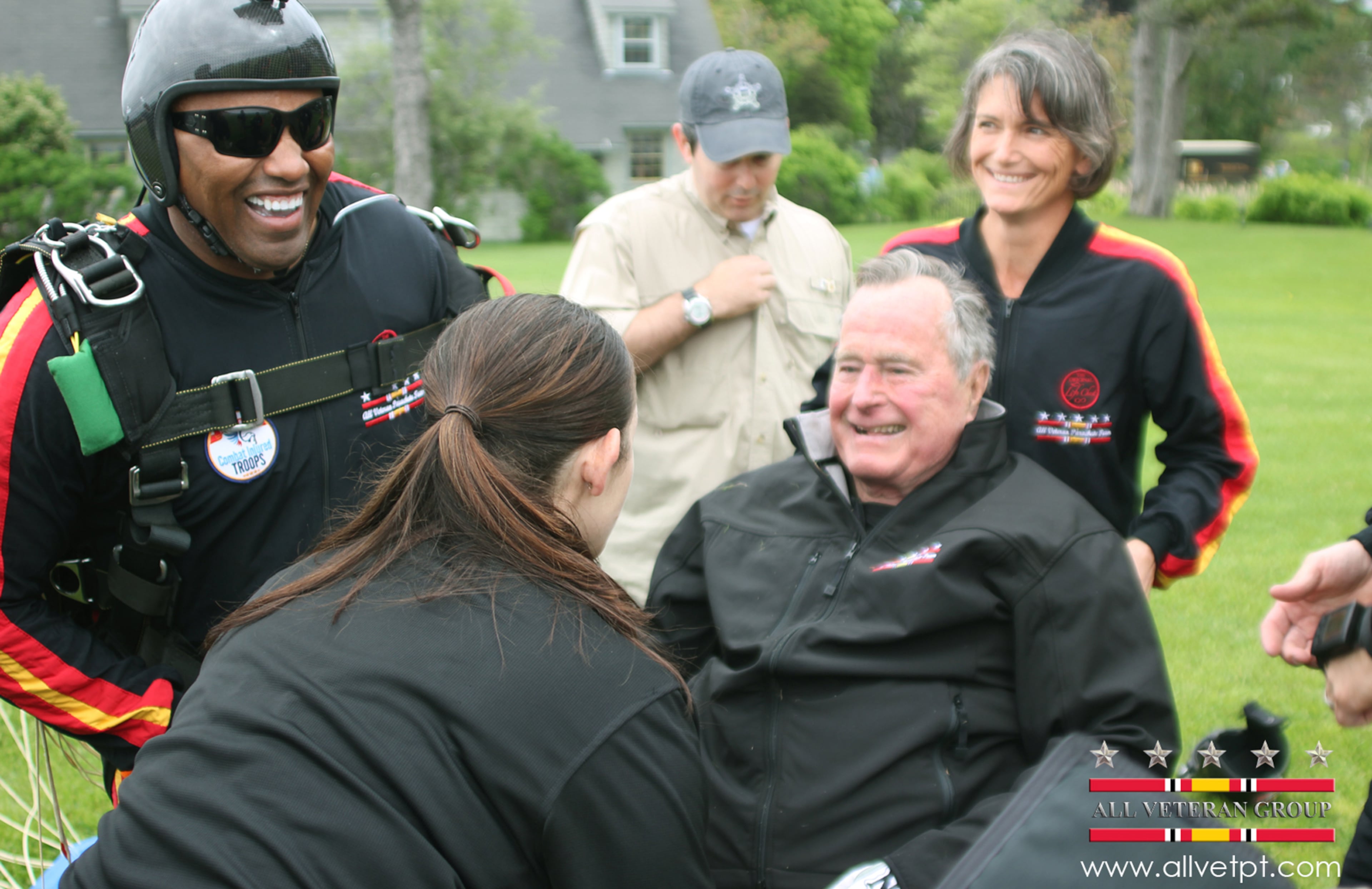 In this photo provided by the All Veteran Parachute Team, former President George H.W. Bush is checked by a doctor with the All Veteran Parachute Team after his landing of a parachute jump on his 90th birthday in Kennebunkport, Maine, Thursday, June 12, 2014. (AP Photo/All Veteran Parachute Team, Kenneth Wasley)