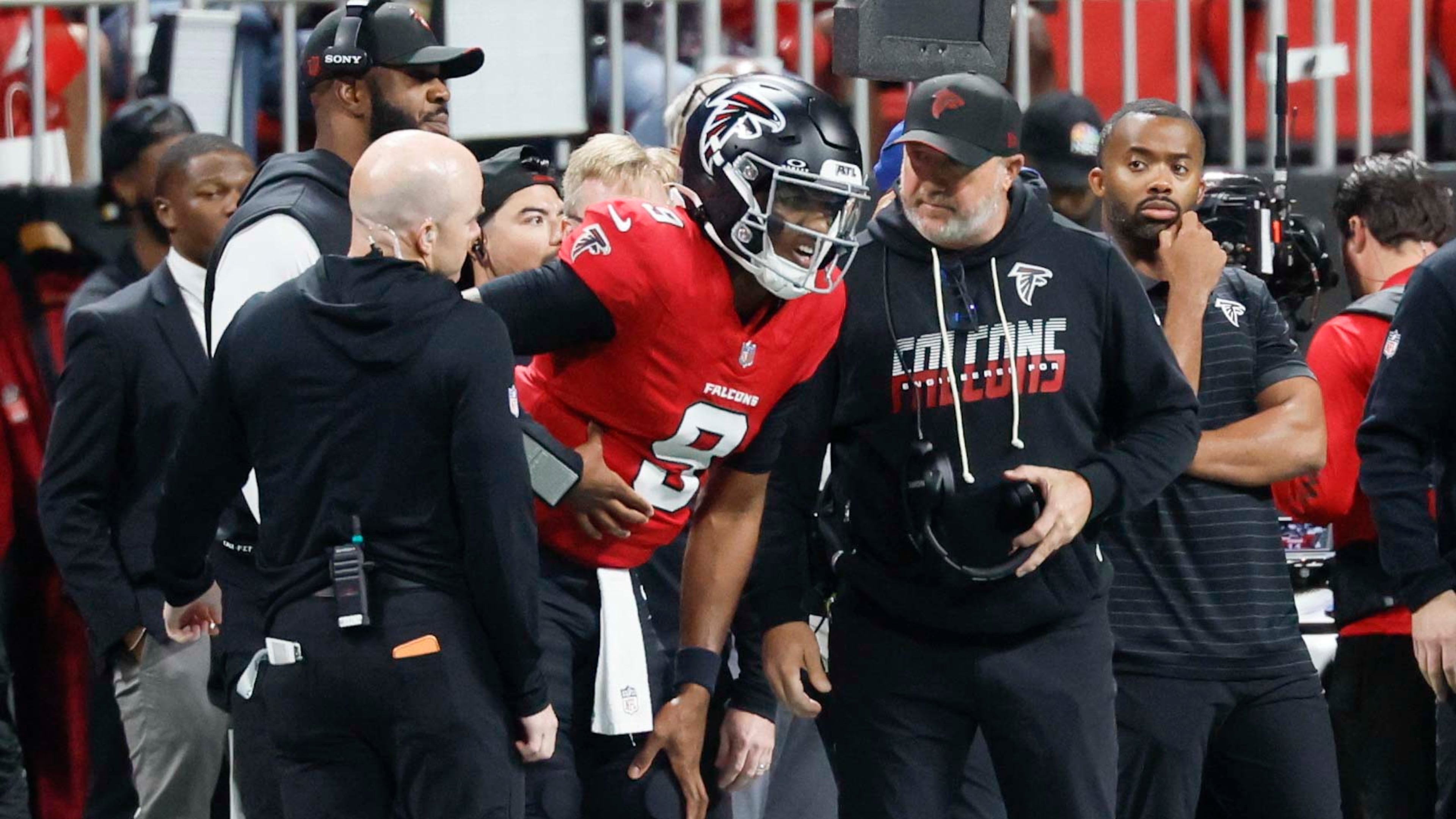 Falcons quarterback Michael Penix Jr. (center) is seen on the sideline in pain, speaking with medical staff, after a play shortly before the end of regulation Sunday, Oct. 11, 2026, against the Ravens at Mercedes-Benz Stadium in Atlanta. (Miguel Martinez/AJC)
