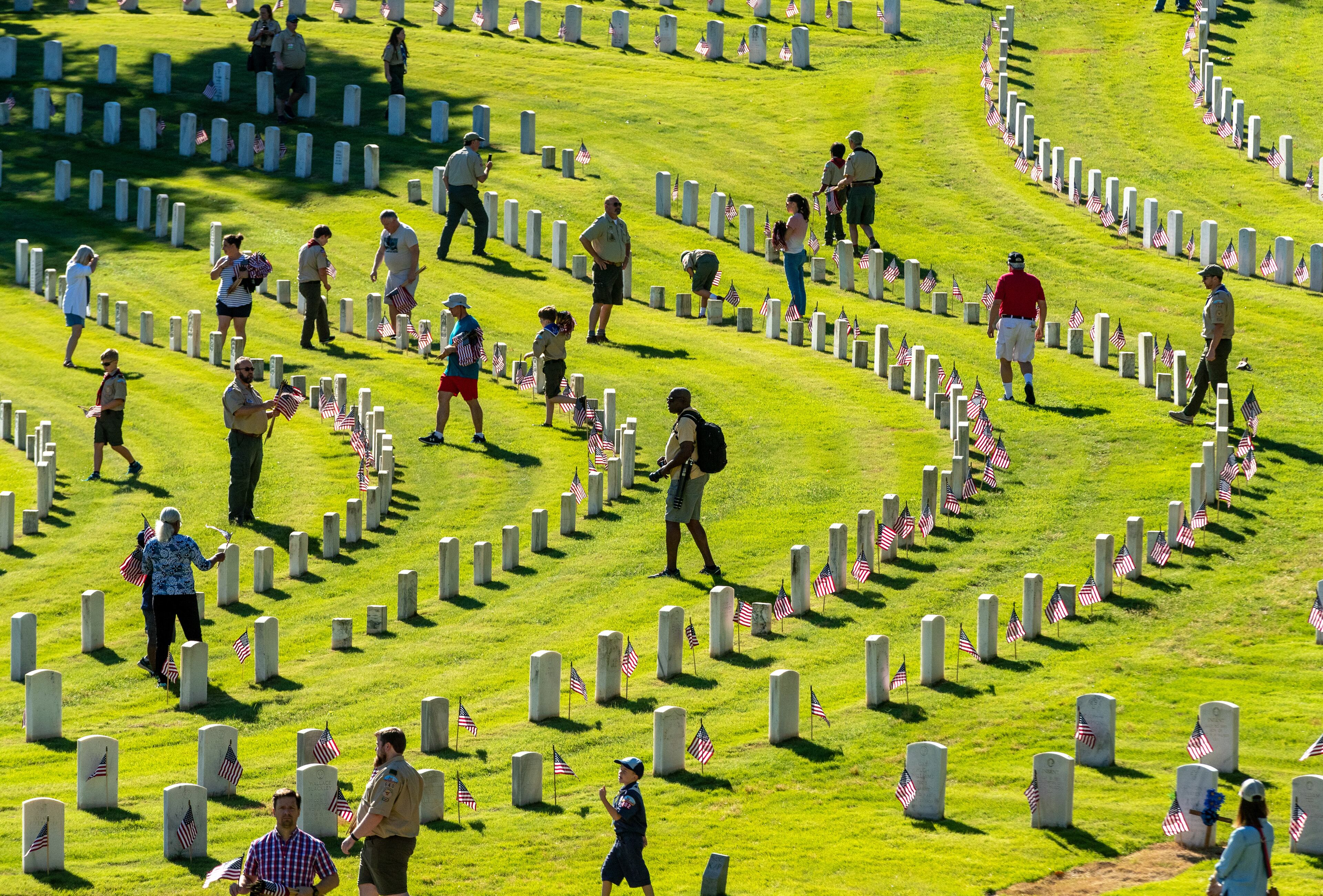 Some of the Eight hundred-forty volunteers walk among the tombstones as they plant American flags in front of every gravesite in preparation for Monday's Memorial Day ceremony at Marietta National Cemetery.Photo: Steve Schaefer / steve.schaefer@ajc.com)