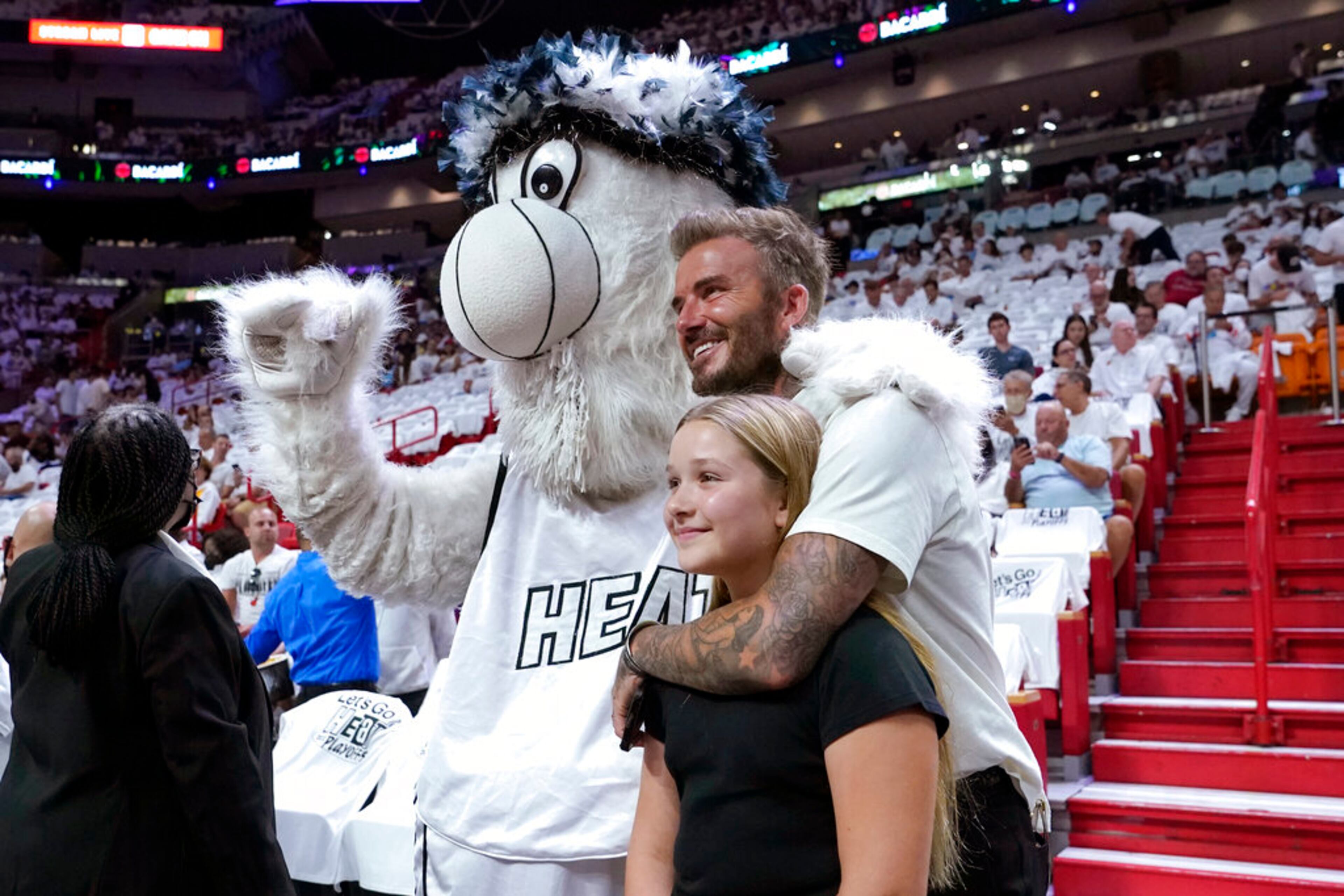 David Beckham and his daughter Harper Seven Beckham pose for a photo with the Miami Heat mascot Burnie during the first half of Game 2 of an NBA basketball first-round playoff series between the Miami Heat and Atlanta Hawks, Tuesday, April 19, 2022, in Miami. (AP Photo/Lynne Sladky)
