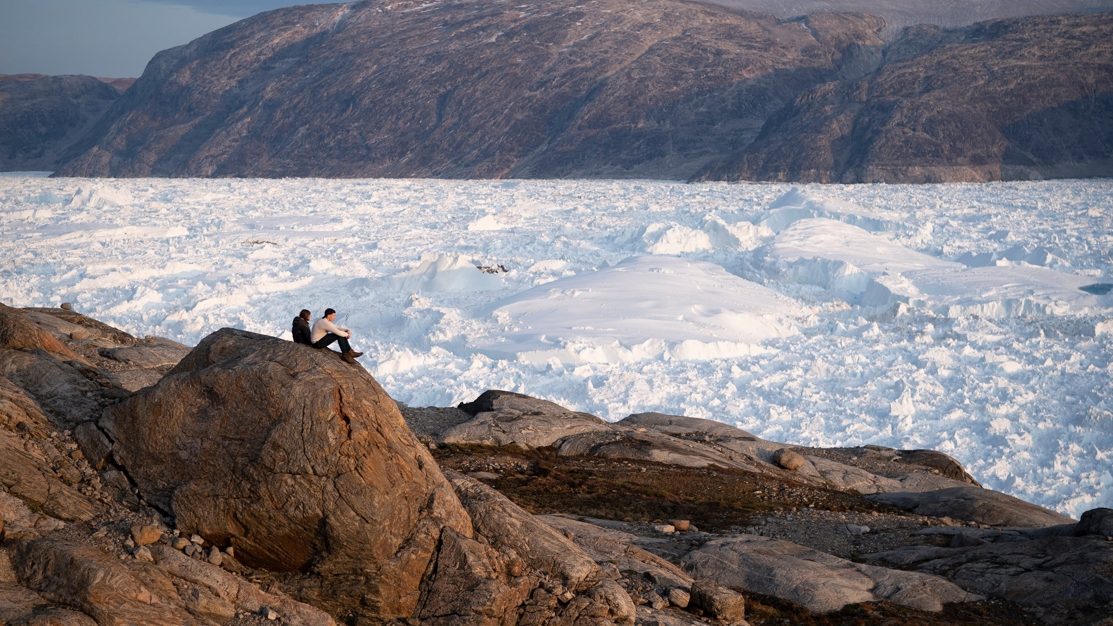 FILE - NYU student researchers sit on top of a rock overlooking the Helheim glacier in Greenland, Aug. 16, 2019. (AP Photo/Felipe Dana, File)