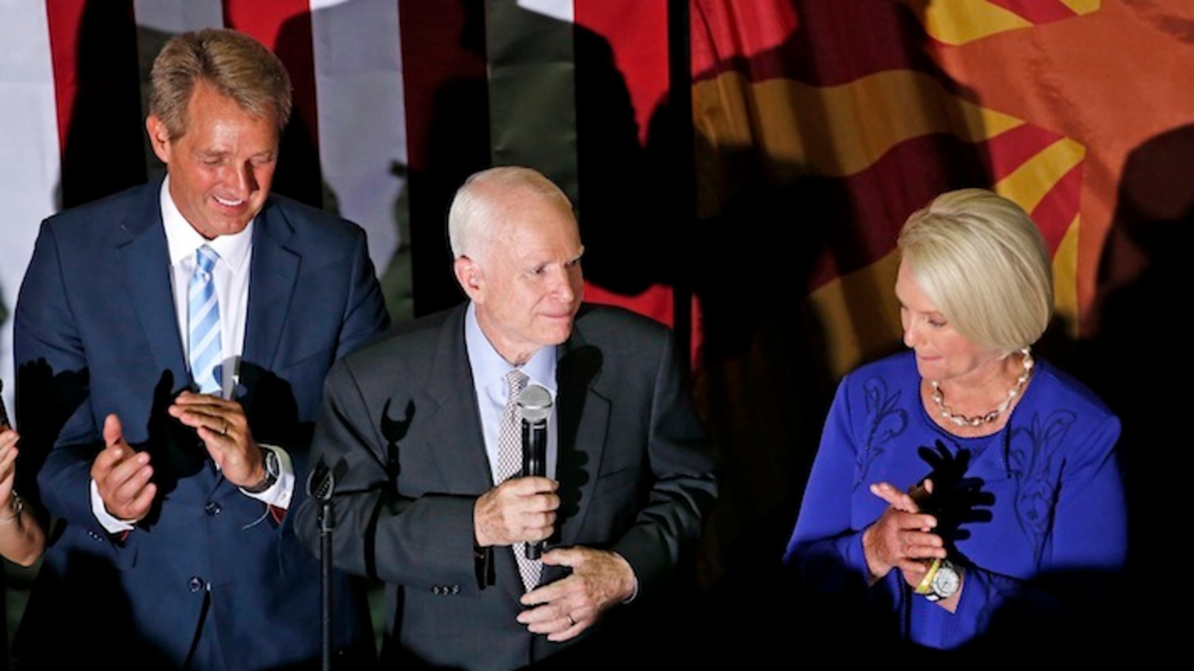 Sen. John McCain, R-Ariz., middle, pauses as he talks to supporters after being declared the winner in the Arizona Republican primary, as his wife Cindy McCain, right, and Sen. Jeff Flake, R-Ariz., left, join him on stage Tuesday, Aug. 30, 2016, in Phoenix. The 80-year-old McCain defeated former state Sen. Kelli Ward and two other Republicans on the ballot. (AP Photo/Ross D. Franklin)