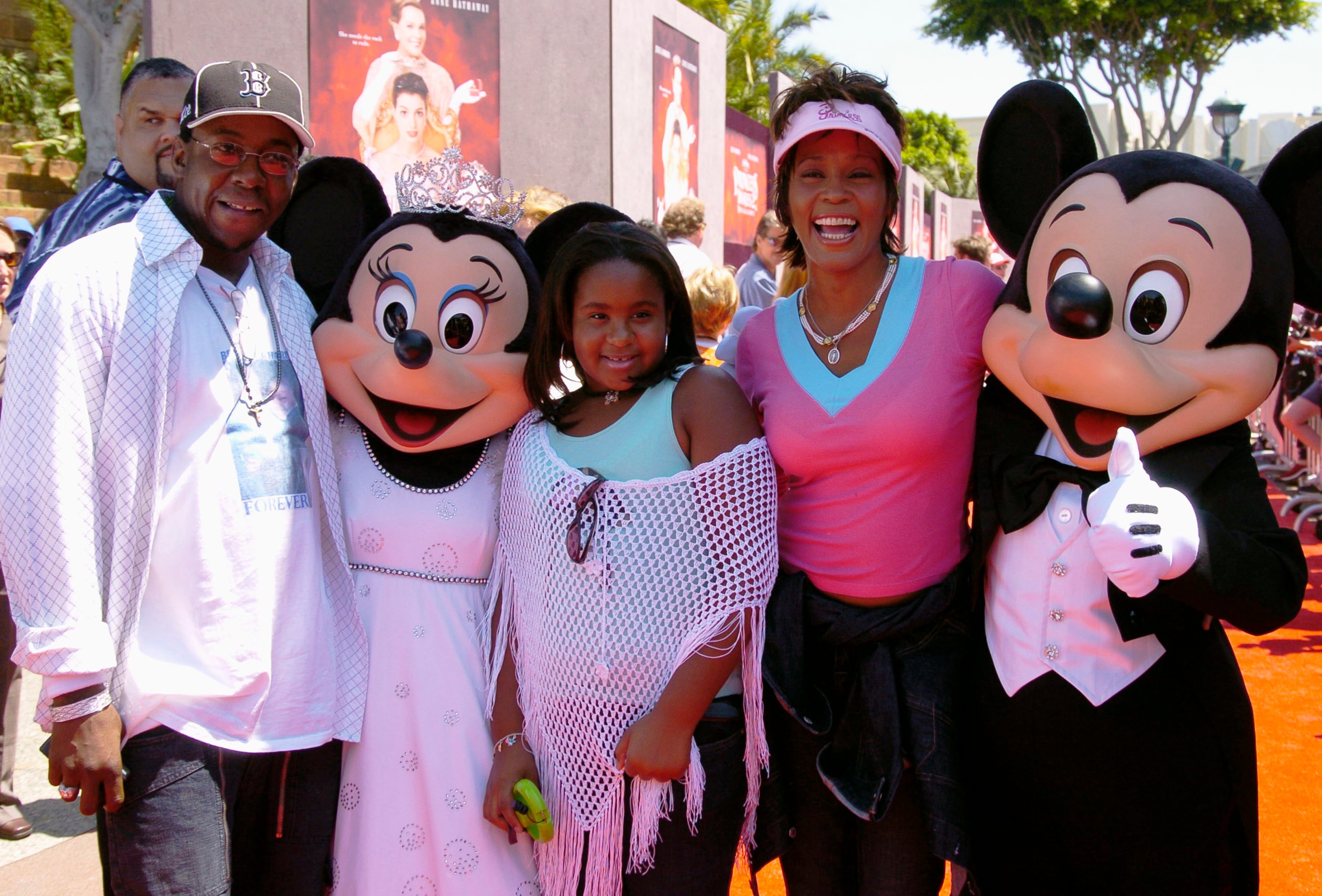 Whitney Houston, Bobby Brown and their daughter Bobbi Kristina are greeted by Mickey Mouse and Minnie Mouse for the premiere of "The Princess Diaries 2" at the Disneyland Resort August 7, 2004 in Anaheim, California. (Photo by Lisa Rose/Disney Parks via Getty Images)