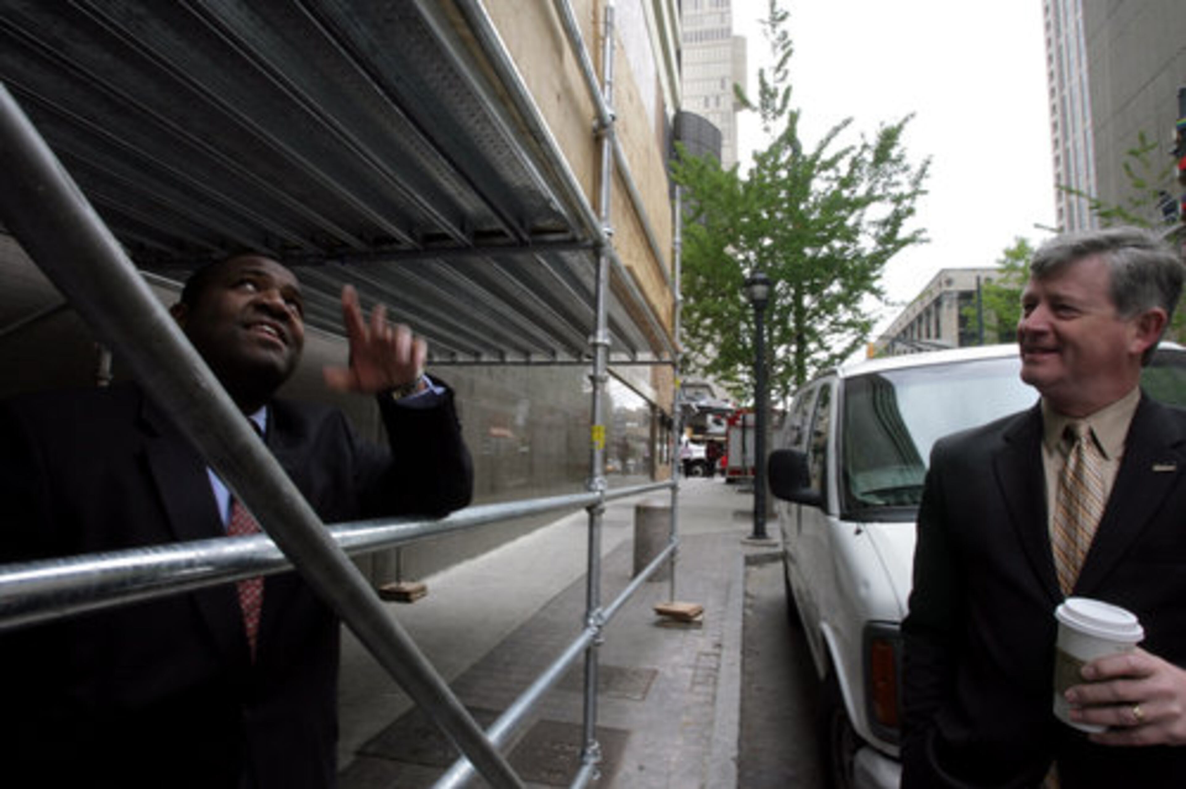 April 14: Atlanta City Council member Ceasar C. Mitchell (left) looked up at storm damage as he talked with Ed Walls, general manager of the Westin Peachtree Plaza Hotel. A month after the tornado, damage downtown was still visible.