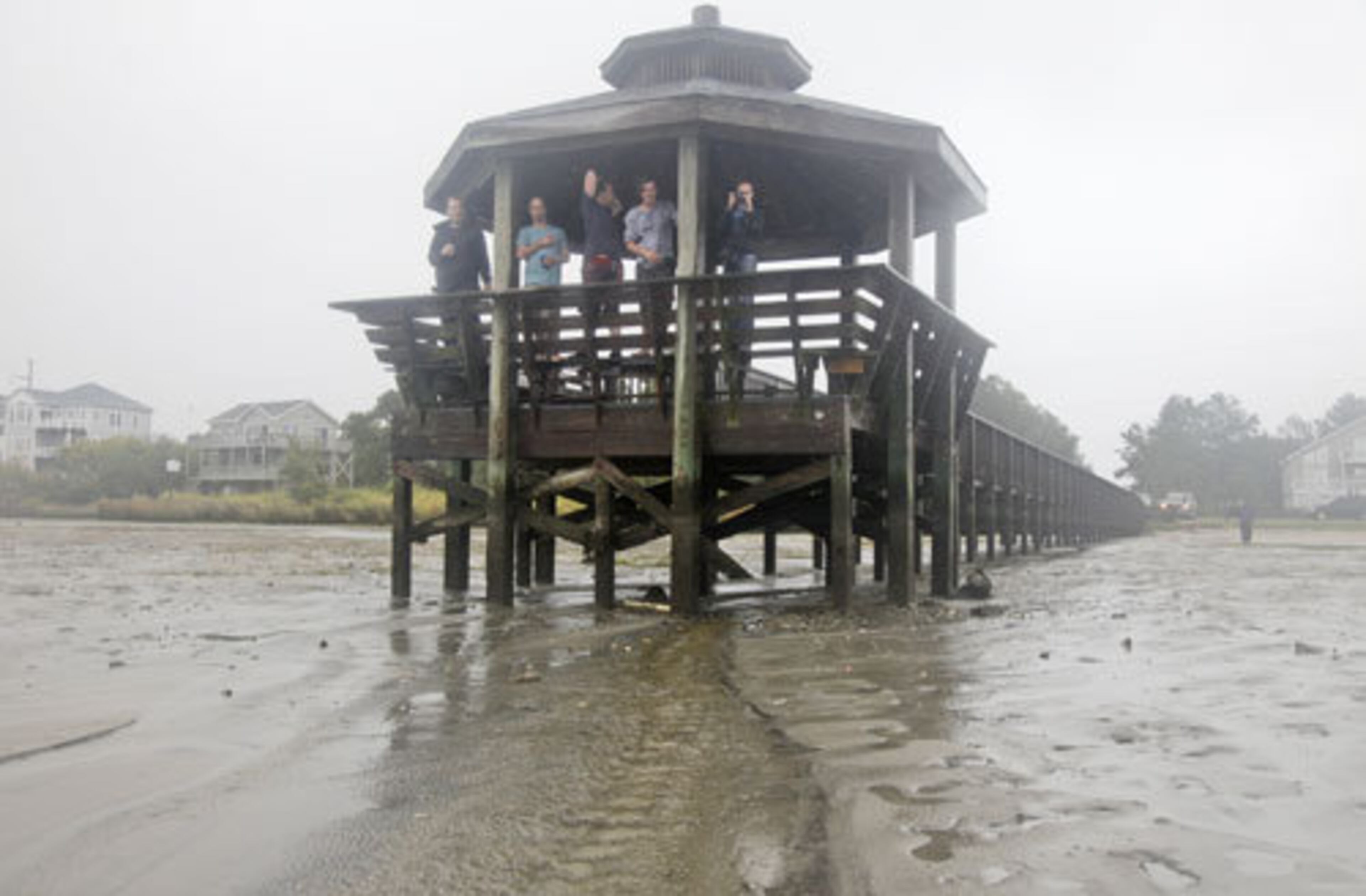 Residents stand on a pier after Hurricane Irene pulled all the water away and into the Albemarle Sound on the Outer Banks in Kill Devil Hills, N.C., Saturday, Aug. 27, 2011 as Hurricane Irene reaches the North Carolina coast. Residents are expecting serious flooding when Irene passes and the tail end of the hurricane will flood the homes seen at rear.