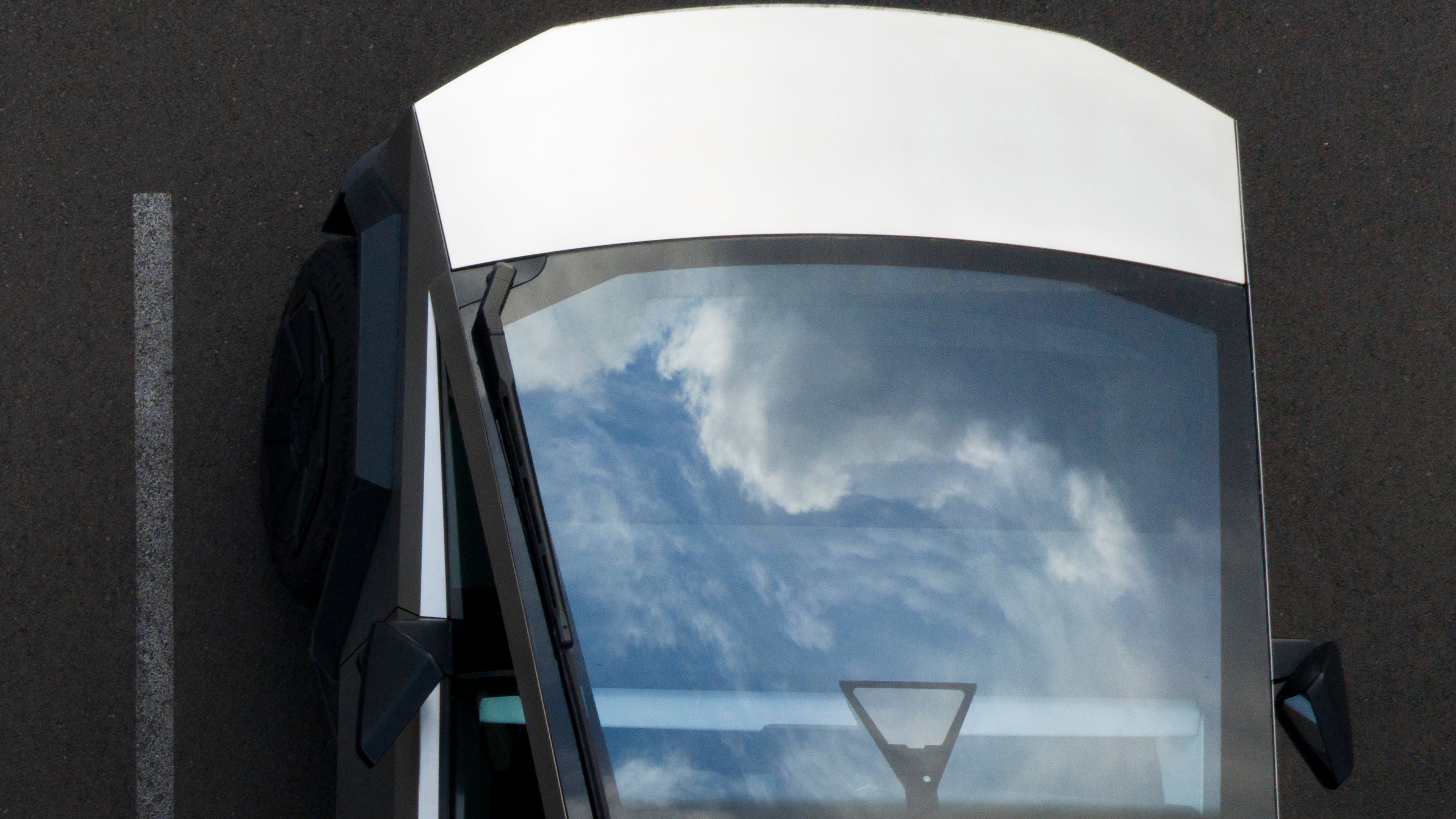 Clouds are reflected on a Tesla cybertruck at a Tesla facility Wednesday, April 15, 2026, in Portland, Ore. (AP Photo/Jenny Kane)
