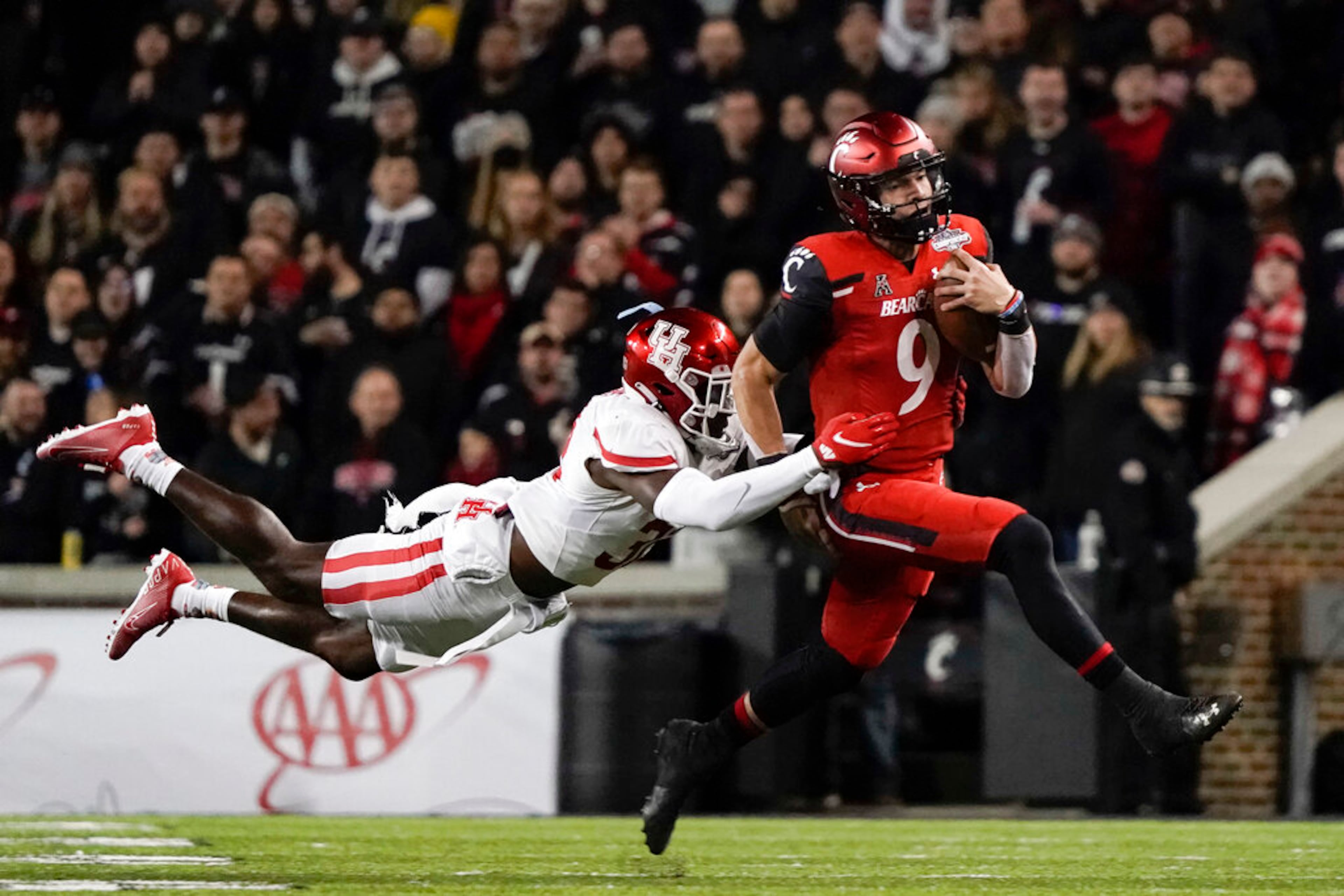 Cincinnati quarterback Desmond Ridder (9) is tackled by Houston's Gervarrius Owens during the second half of the American Athletic Conference championship NCAA college football game Saturday, Dec. 4, 2021, in Cincinnati. (AP Photo/Jeff Dean)