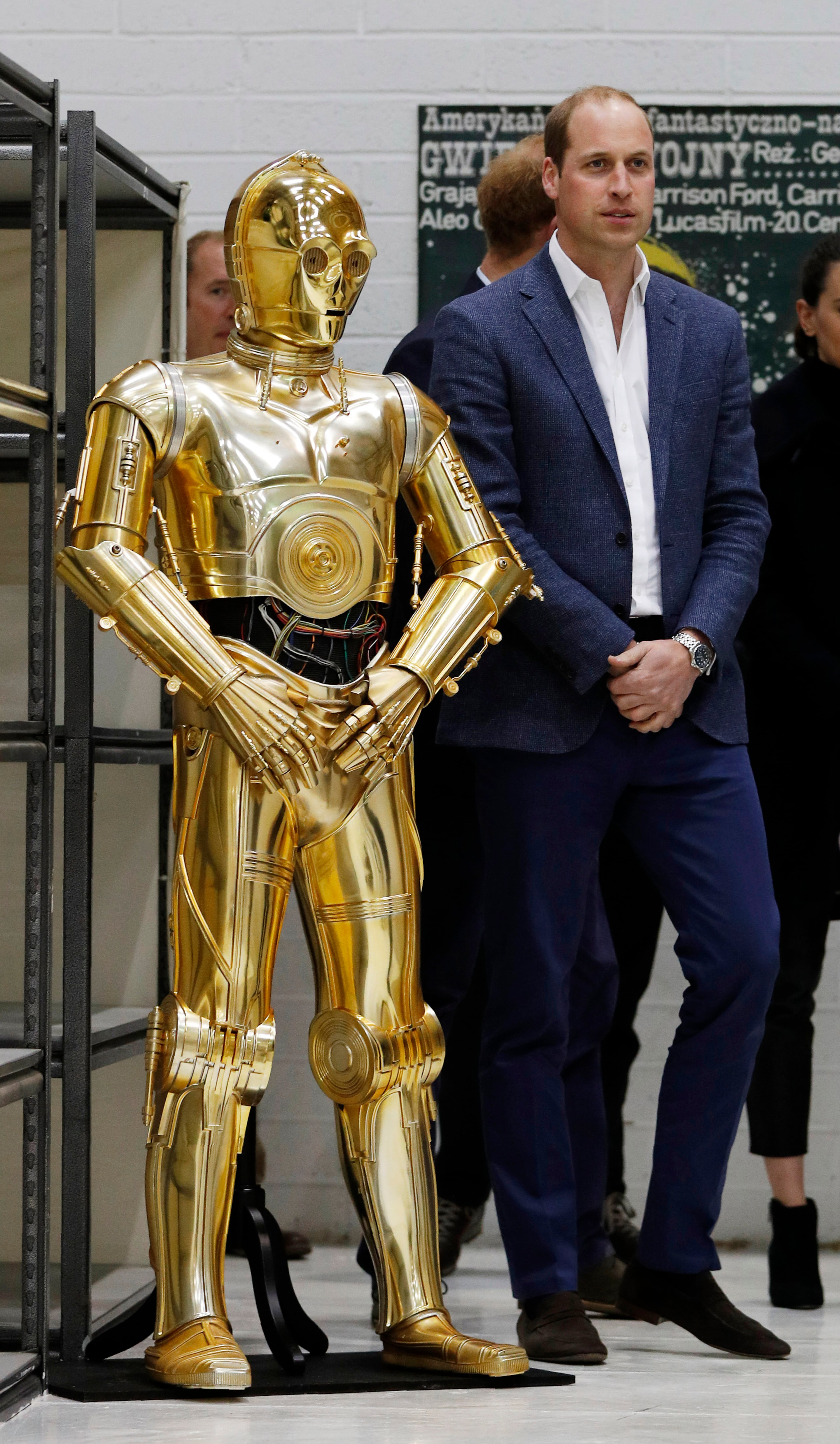 IVER HEATH, ENGLAND - APRIL 19: Prince William, Duke of Cambridge (R) poses next to the droid C3P0 from Star Wars as they visit the creature and droid department at Pinewood studios on April 19, 2016 in Iver Heath, England. Prince William and Prince Harry are touring Pinewood studios to visit the production workshops and meet the creative teams working behind the scenes on the Star Wars films. (Photo by Adrian Dennis-WPA Pool/Getty IMages)
