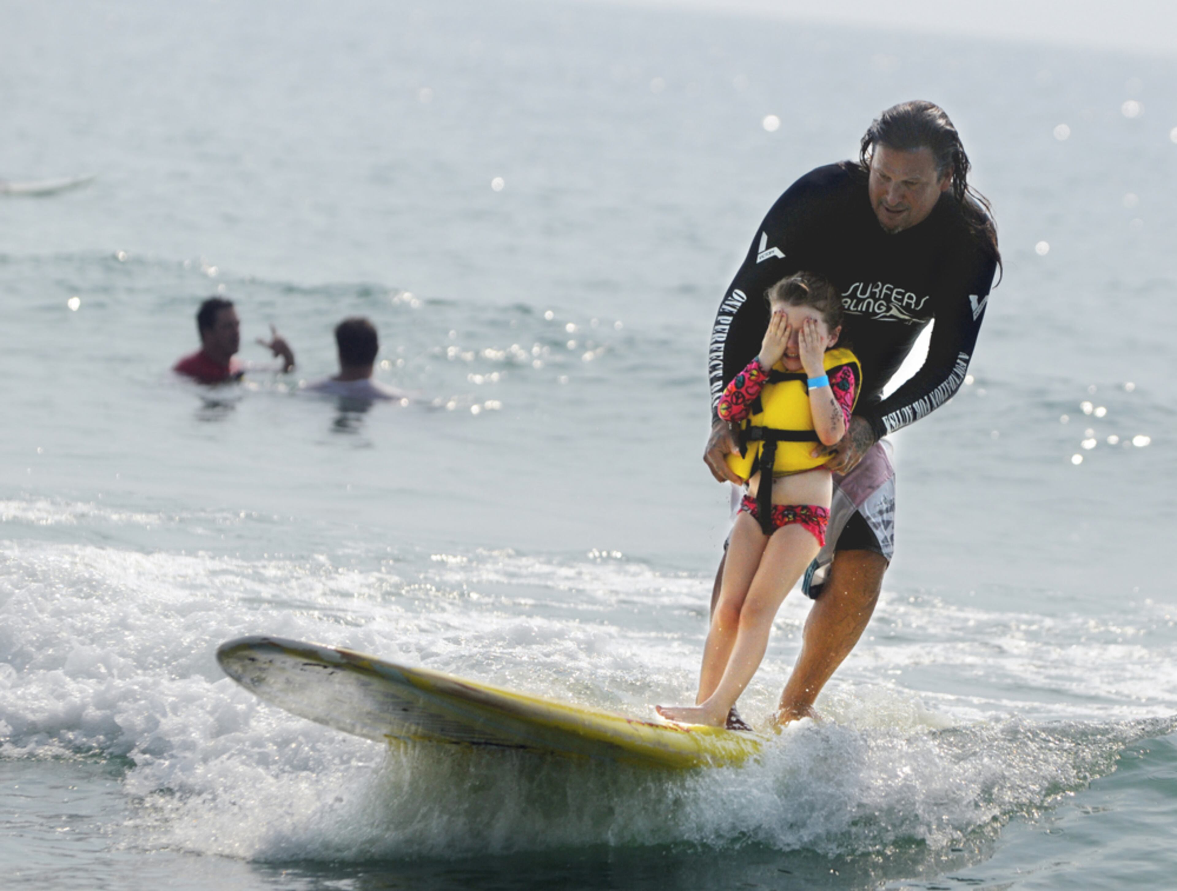 CATCHING SOME WAVES--Izzy Paskowitz helps Nixee Grace Chanowsky, 4, catch a wave Monday, Aug. 18, 2014 at Wrightsville Beach, N.C. during the Annual Surfers Healing event for children with autism. Hundreds of people made their way to the beach to watch and cheer on the camp that was founded by Israel and Danielle Paskowitz. (AP Photo/The Star-News, Mike Spencer)