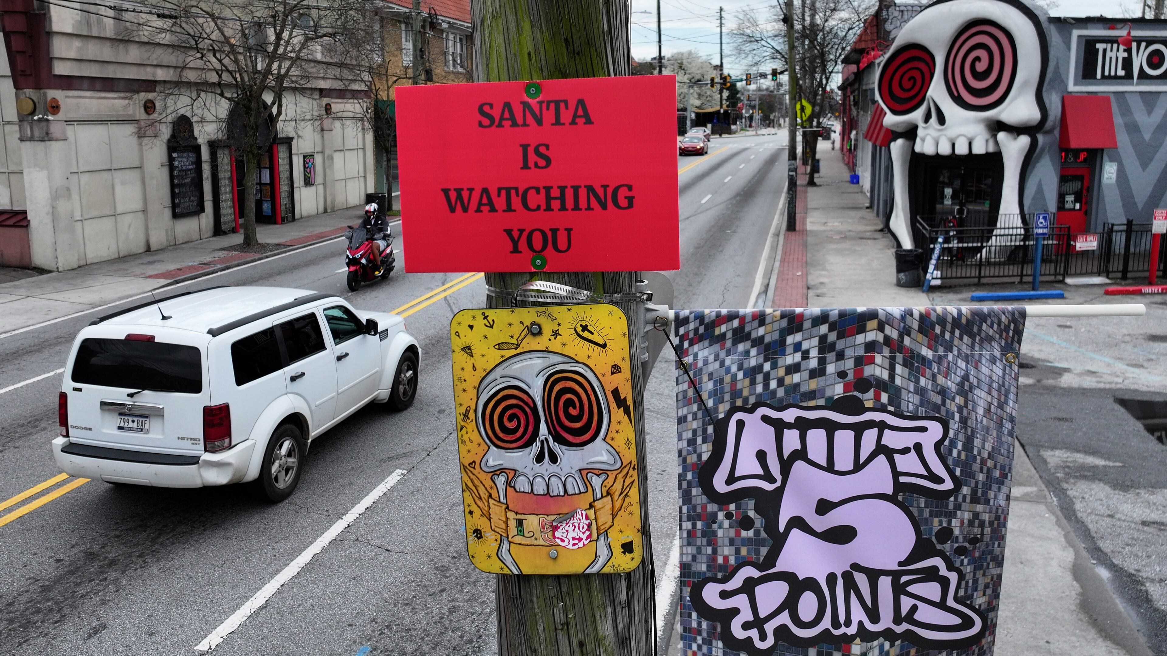 Cars pass by a sign that reads "SANTA IS WATCHING YOU" on a utility pole on Moreland Avenue near the Vortex Bar and Grill in Little Five Points, Atlanta, Tuesday, March 10, 2026. (Hyosub Shin/AJC)