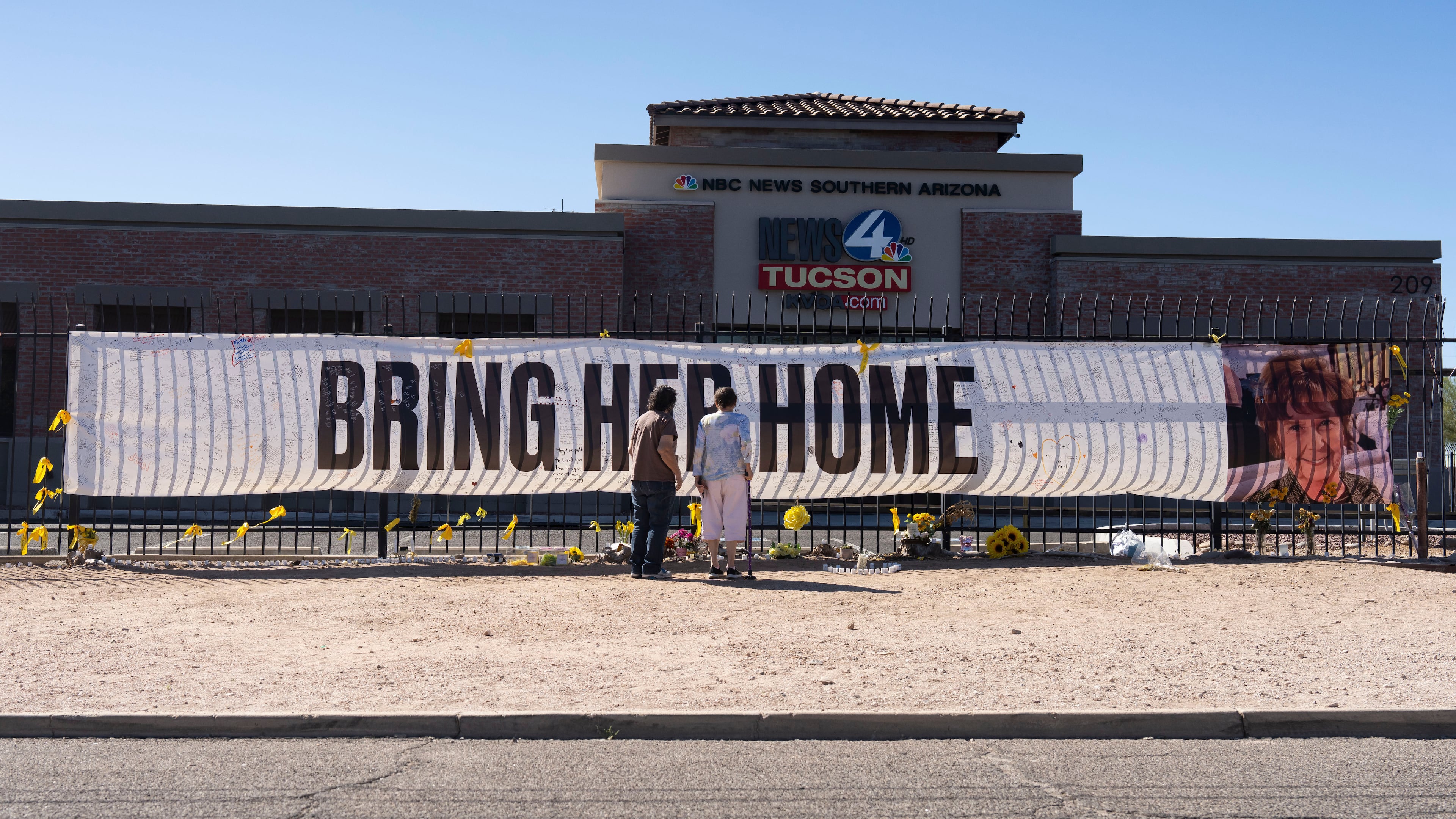 FILE - People visit a banner for Nancy Guthrie, the missing mother of "Today" show host Savannah Guthrie, outside the KVOA Newsroom in Tucson, Ariz., on March 6, 2026. (AP Photo/Rebecca Noble, File)