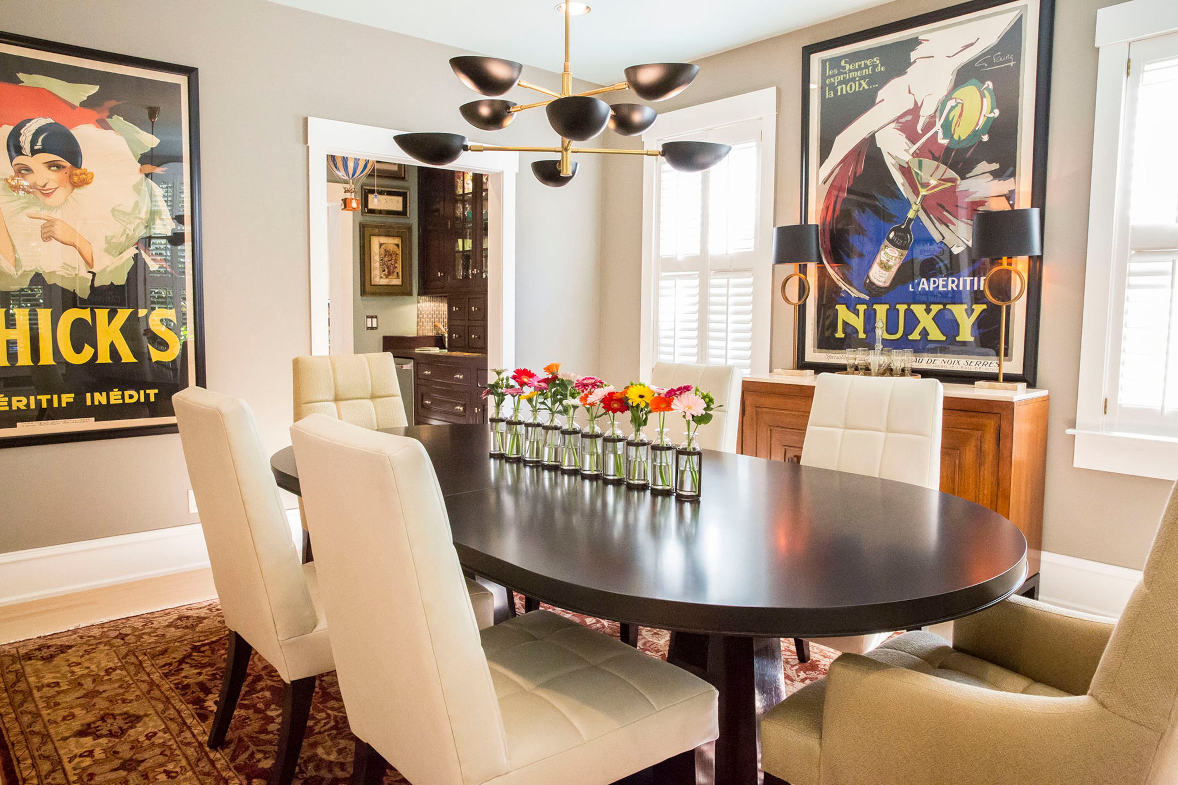 A Circa Lighting chandelier casts a striking figure above the Barbara Barry table and chairs in the dining room. Large French advertisements are a design theme throughout the home.