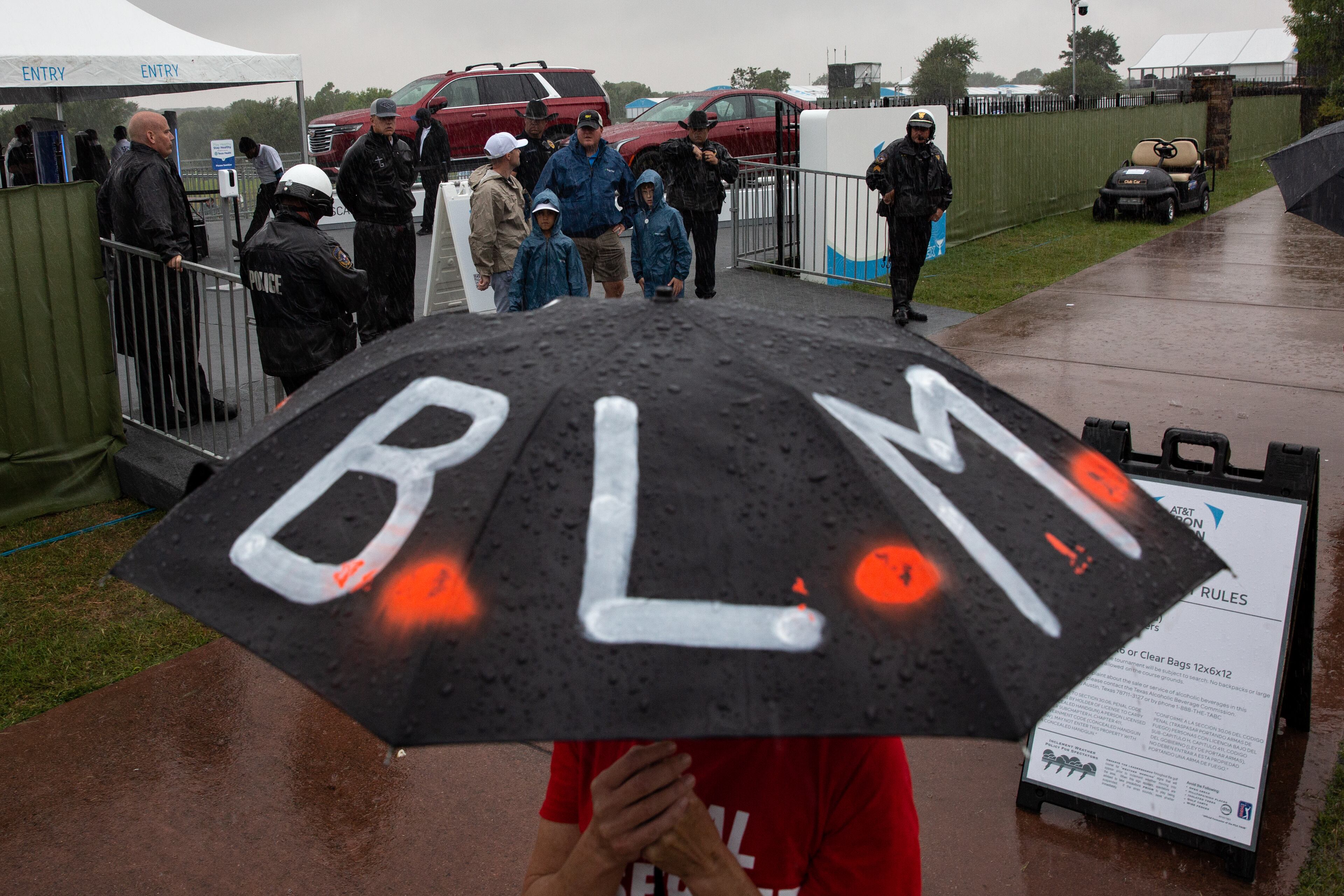 Shannon Borders shields herself from the rain as her and other demonstrators gather at the entrance of the Byron Nelson PGA golf tournament at TPC Craig Ranch in McKinney, Texas to spread awareness of the death of Marvin Scott III. (Shelby Tauber/The Dallas Morning News/TNS)