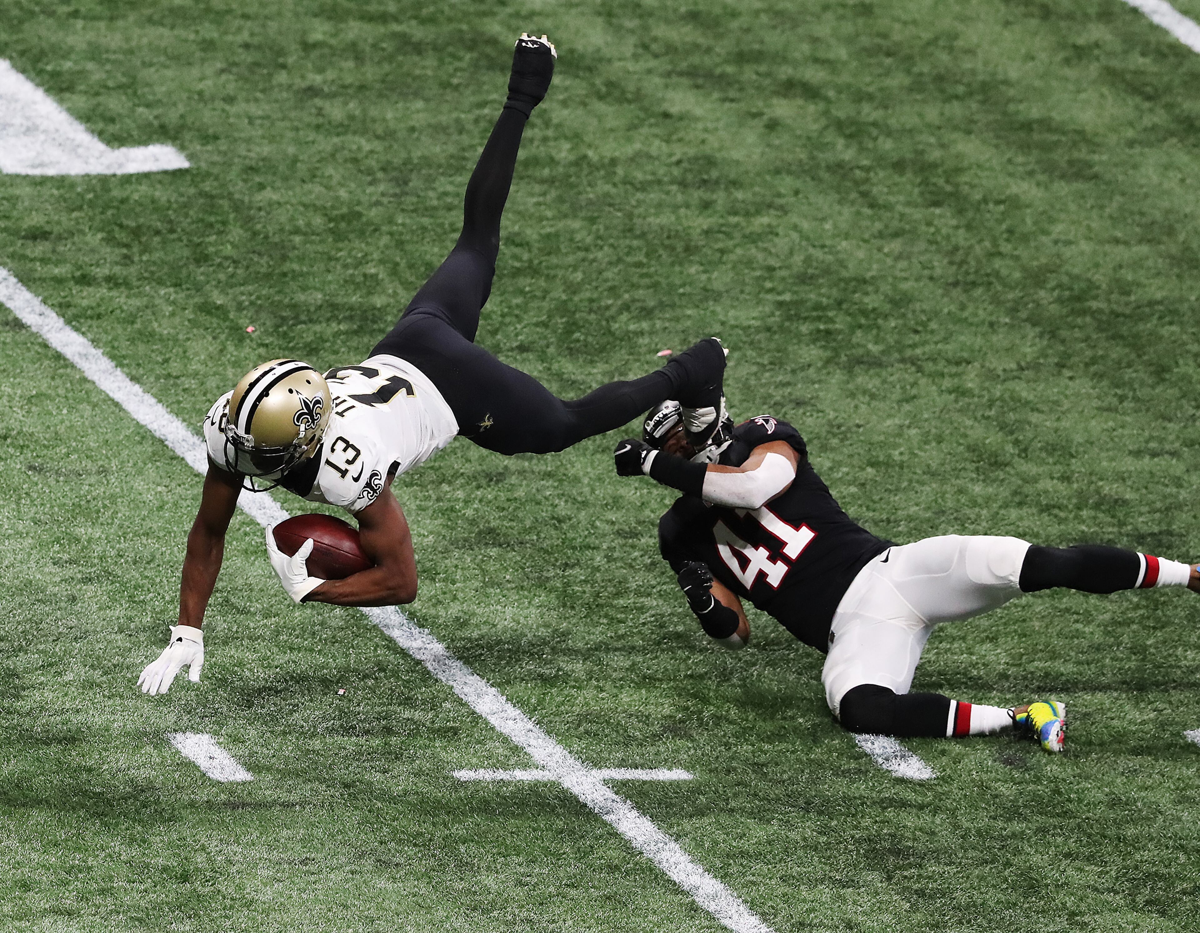 New Orleans Saints wide receiver Michael Thomas picks up yardage on a catch and is sent flying by Atlanta Falcons safety Sharrod Neasman during the fourth quarter Sunday, Dec. 6, 2020, at Mercedes-Benz Stadium in Atlanta. (Curtis Compton / Curtis.Compton@ajc.com)