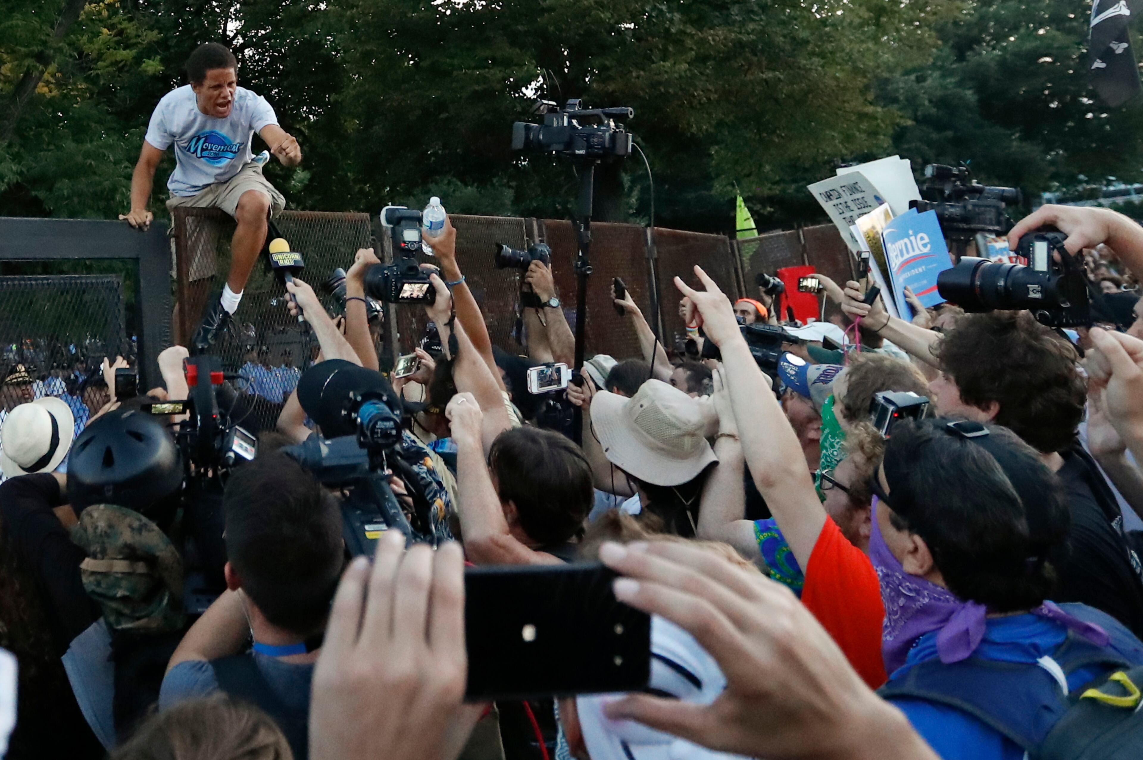 A protester climbs over the fence near the AT&T Station in Philadelphia, Tuesday, July 26, 2016, during the second day of the Democratic National Convention. (AP Photo/Alex Brandon)