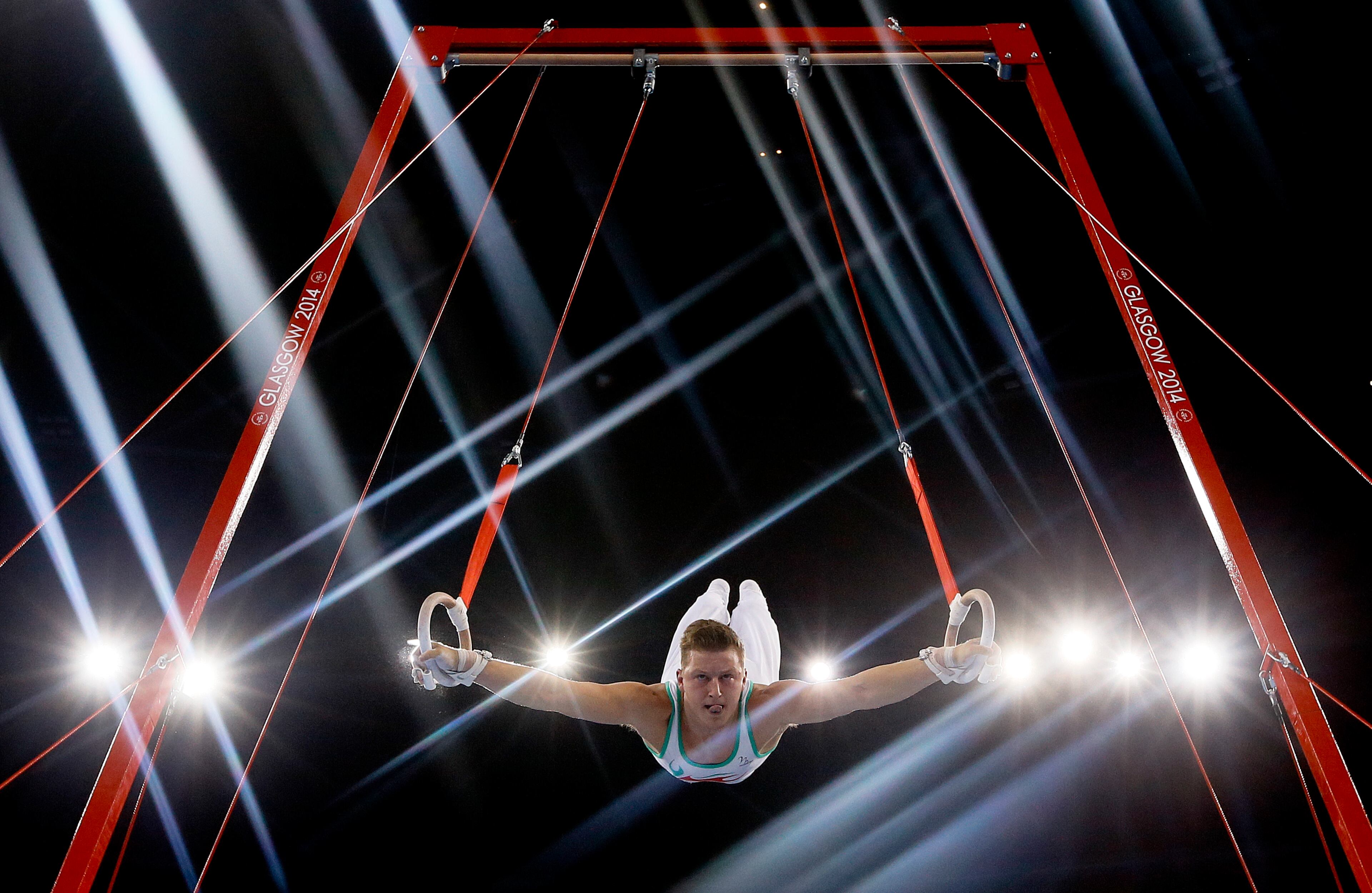 Lights flare as Harry Owen of Wales performs on the rings during the Men's All-Around gymnastics competition at the Scottish Exhibition Conference Centre during the Commonwealth Games 2014 in Glasgow, Scotland, Wednesday July 30, 2014.