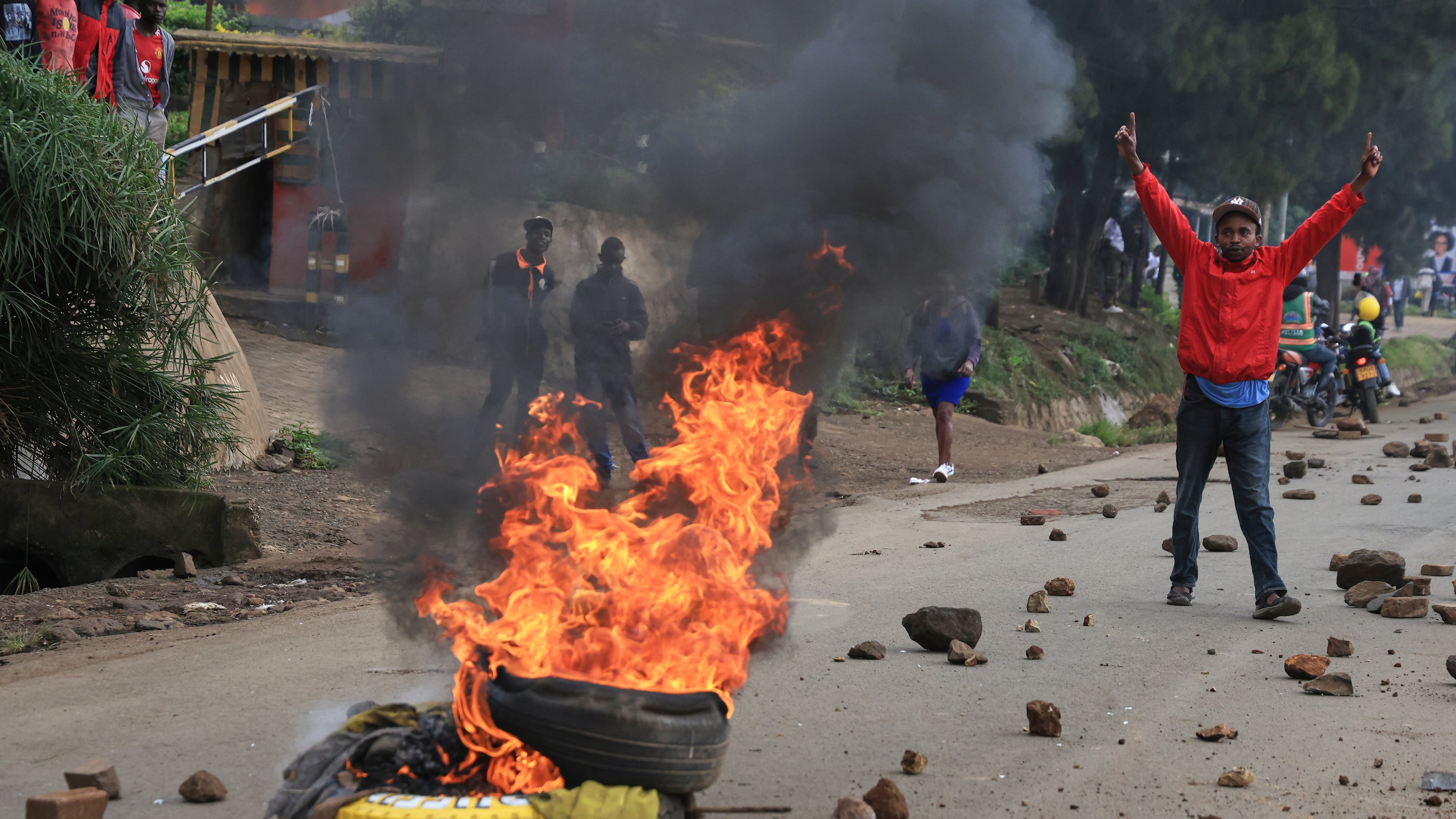 A man demonstrates near a fire during a public transport strike over fuel prices in Nairobi, Kenya, Monday, May 18, 2026. (AP Photo/Andrew Kasuku)