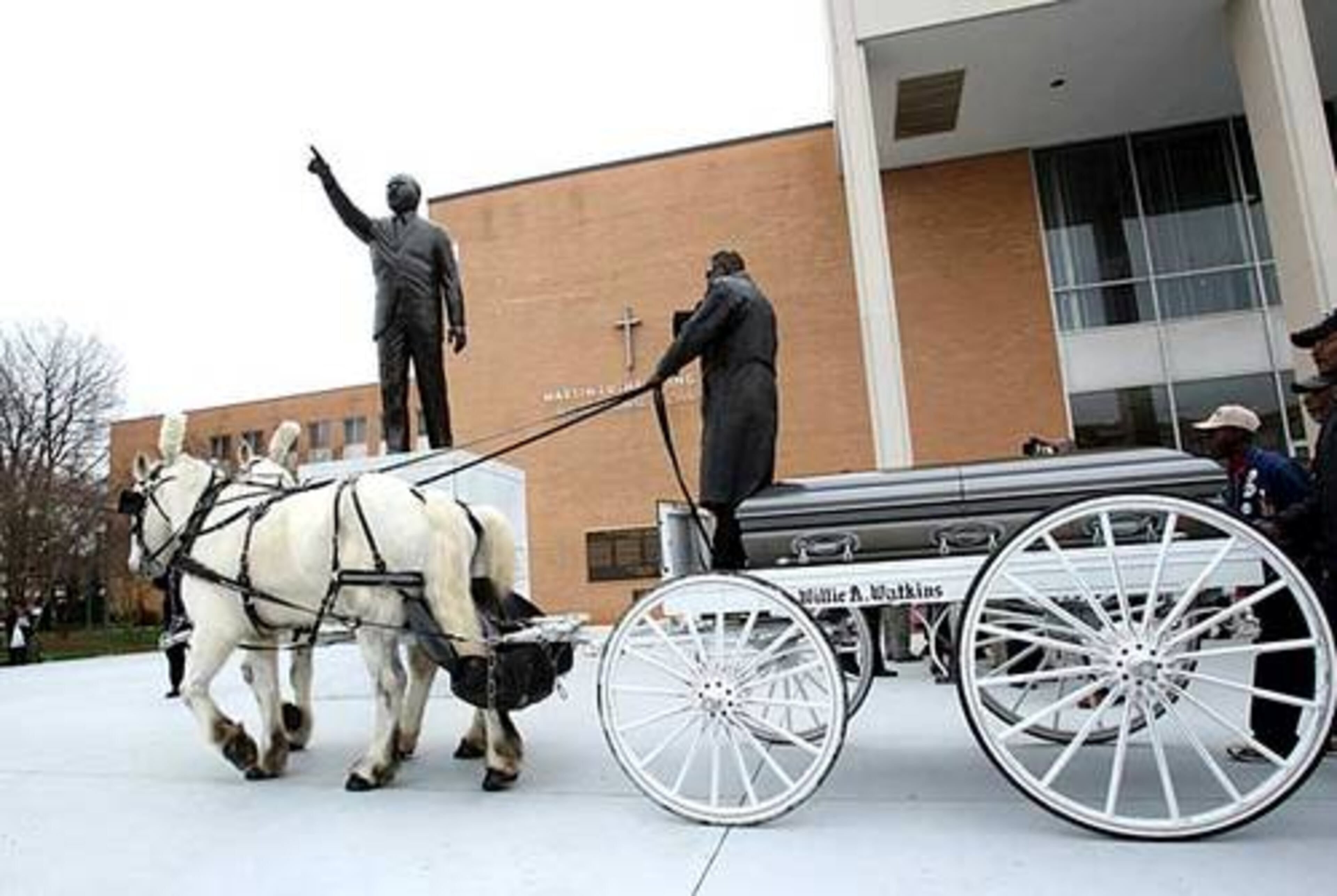 Larry Randall takes off his hat as he passes the statue of Dr. Martin Luther King Jr. with the body of the Rev. James Orange on Saturday.
