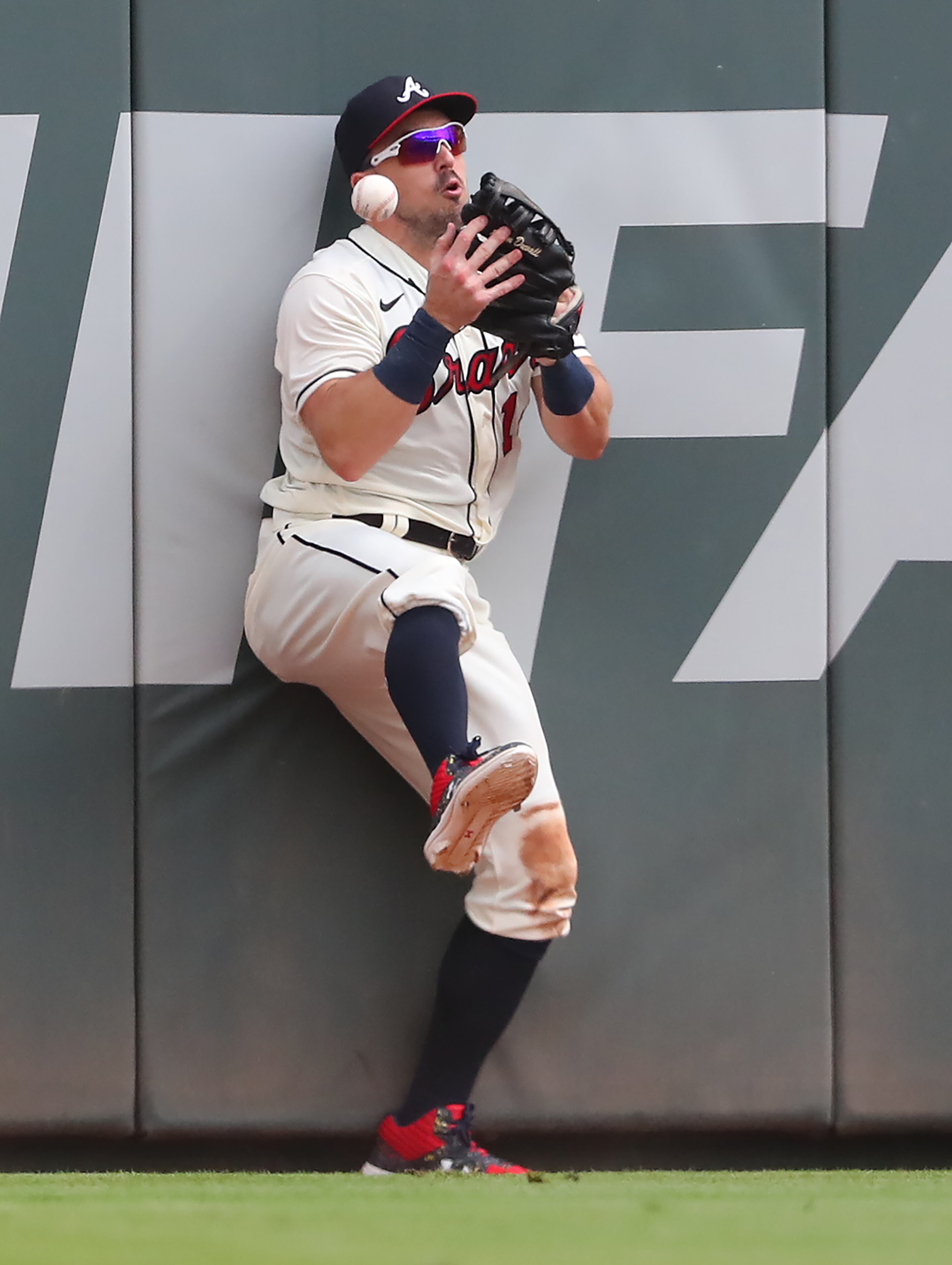 A fly ball by Washington's Alcides Escobar comes loose from Braves outfielder Adam Duvall's glove as he hits the wall during the 9th inning Sunday, Aug. 8, 2021, at Truist Park in Atlanta. The Nationals scored a run in the inning. (Curtis Compton / Curtis.Compton@ajc.com)