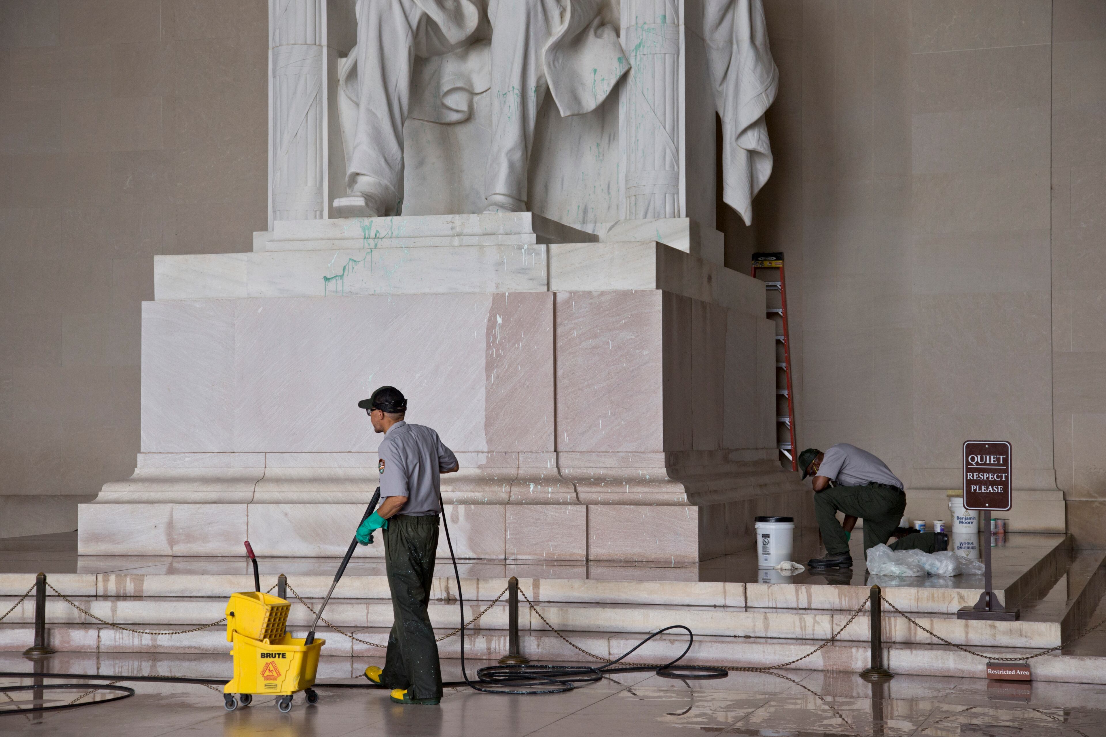 National Park Service workers clean the Lincoln Memorial in Washington, Friday, July 26, 2013, after someone splattered green paint on the statue of the 16th president and the floor area. Police say the apparent vandalism was discovered early Friday morning with no words, letters or symbols were visible in the paint. (AP Photo/J. Scott Applewhite)