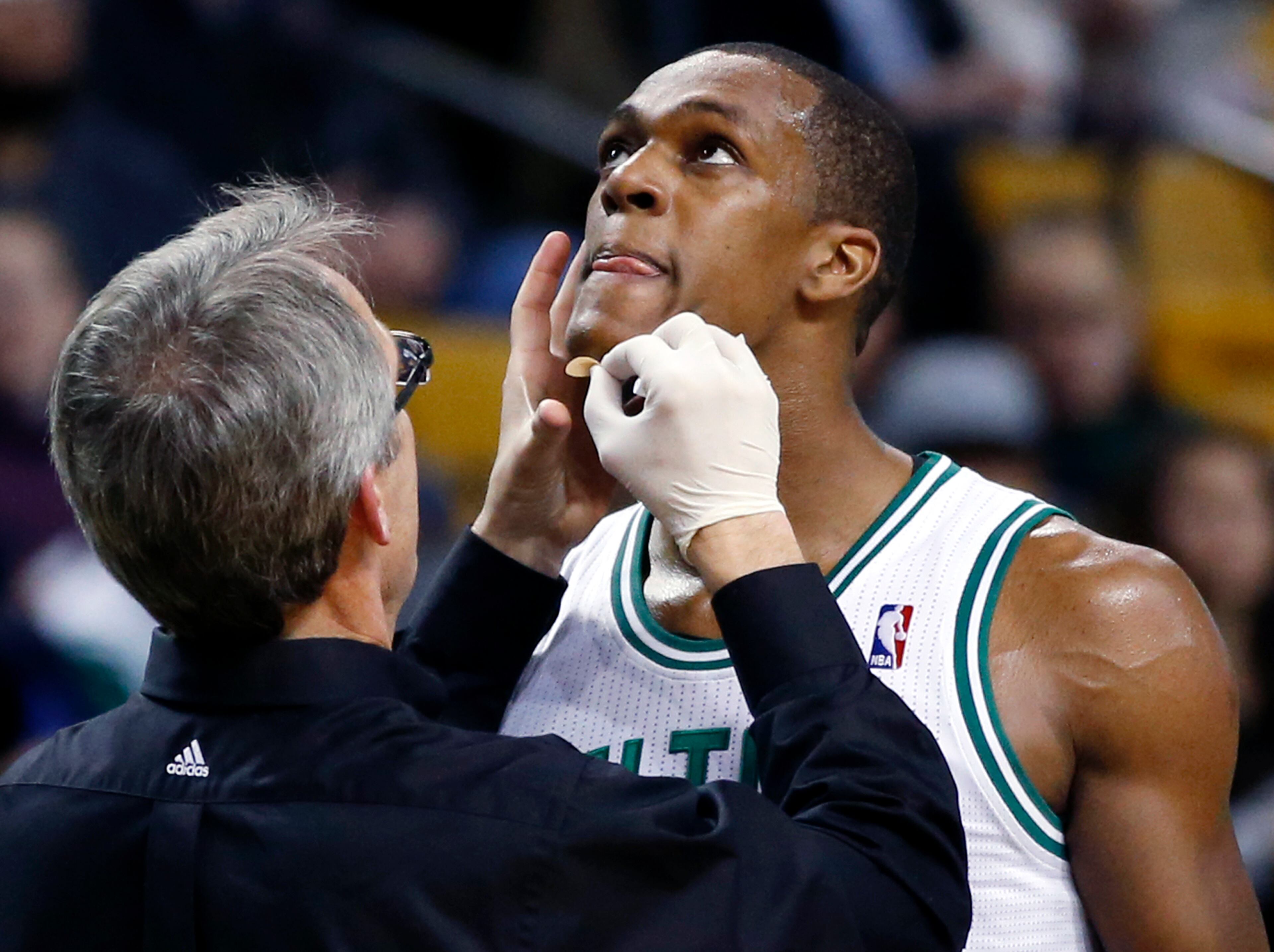 Boston Celtics guard Rajon Rondo receives treatment on his chin from trainer Ed Lacerte after cutting himself diving for the ball against the Atlanta Hawks during the first quarter of an NBA basketball game in Boston, Wednesday, Feb. 26, 2014. (AP Photo/Elise Amendola)