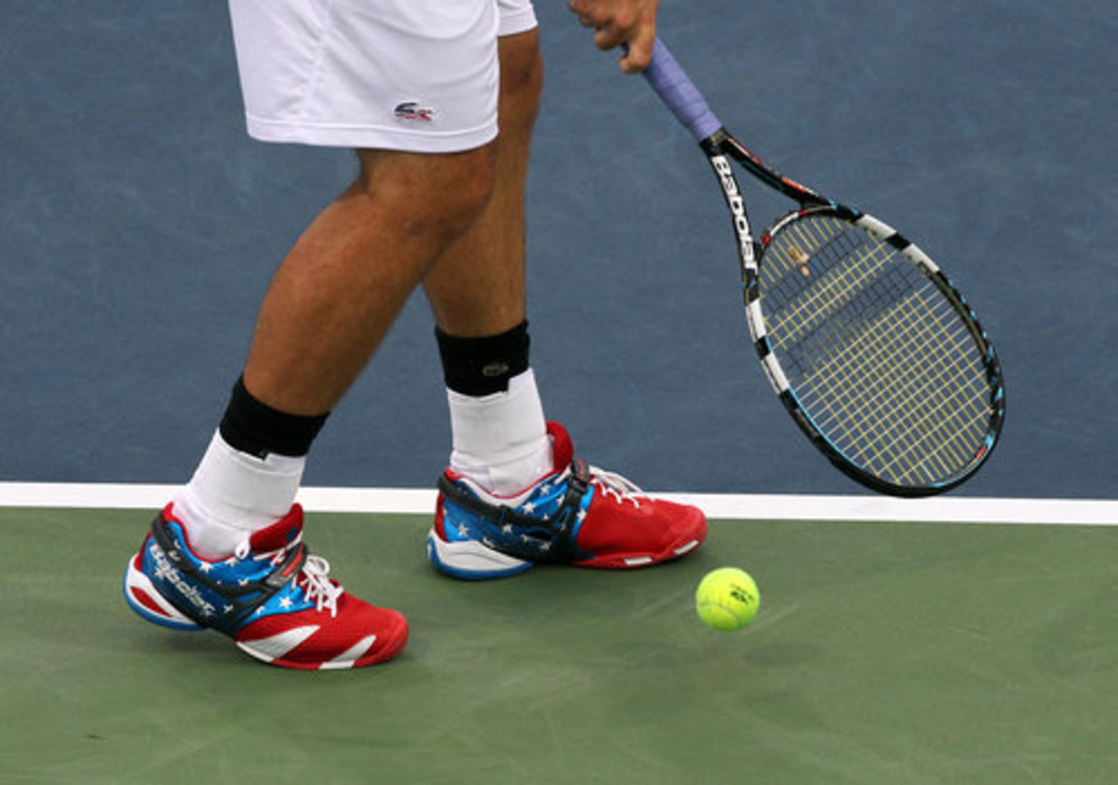 Andy Roddick (USA), a member of the US Olympic team, sports a pair of stars and stripes shoes as he serves to Michael Russell (USA) during quarterfinals play in the Atlanta Open on Friday, July 20, 2012.