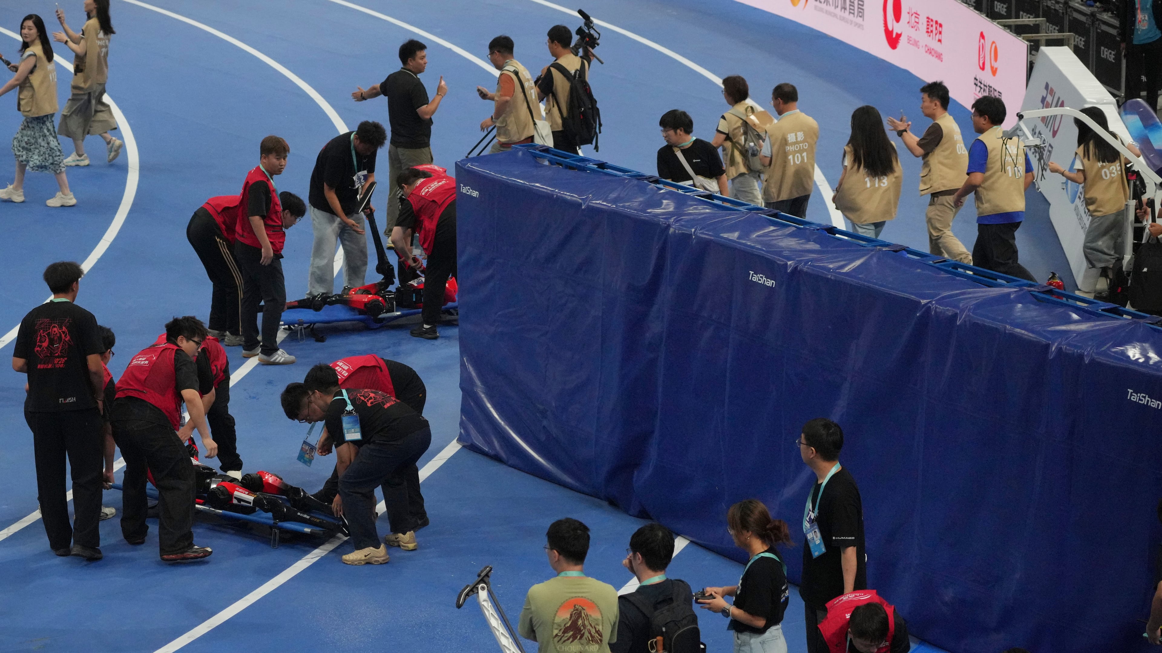 Humanoid robots are carried off the track after competing in the 100m race during the World Humanoid Robot Games in Beijing, Tuesday, Aug. 25, 2026. (AP Photo/Achmad Ibrahim)