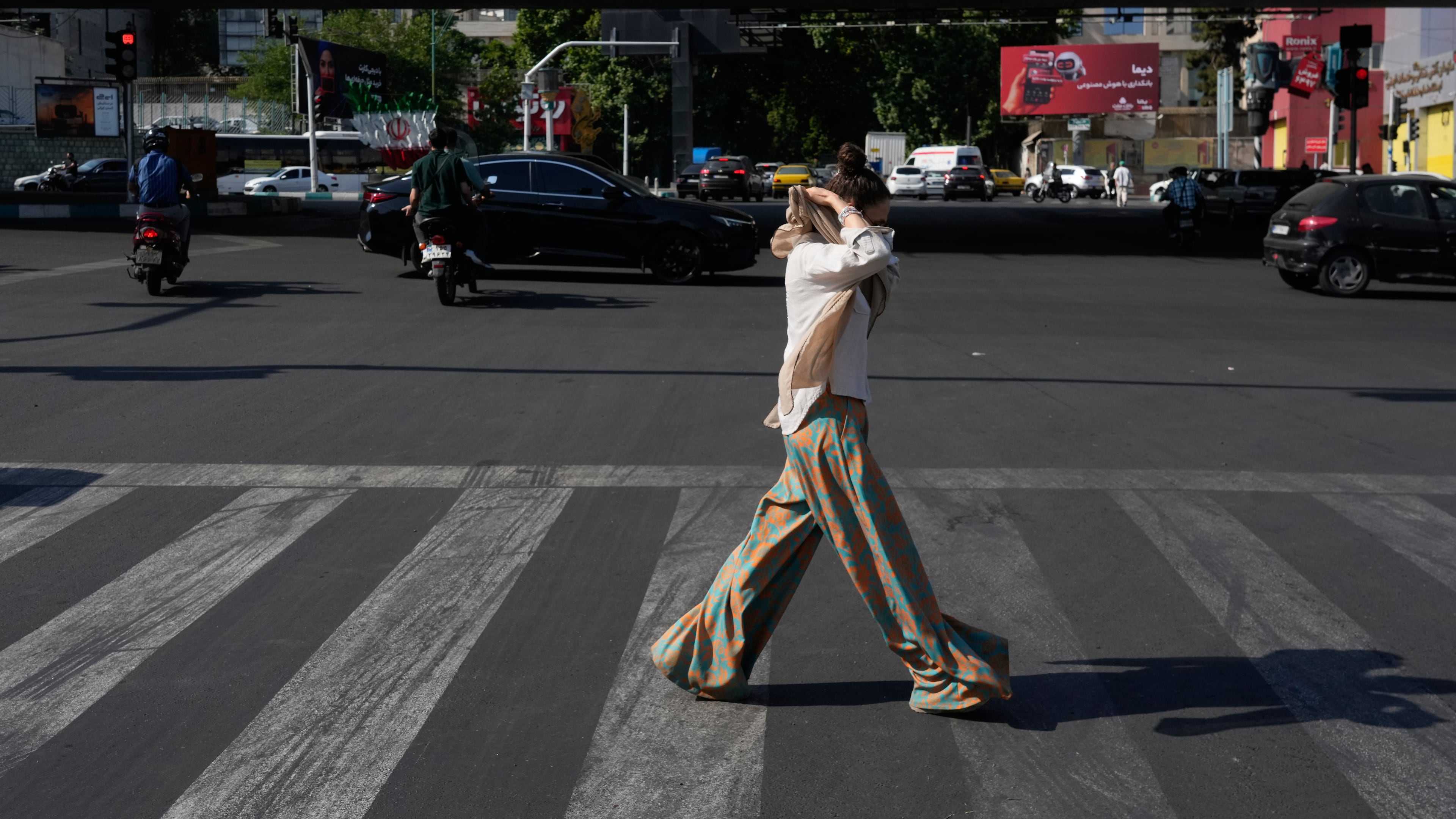 A woman adjusts her headscarf as she crosses an intersection in northern Tehran, Wednesday, June 10, 2026. (AP Photo/Vahid Salemi)