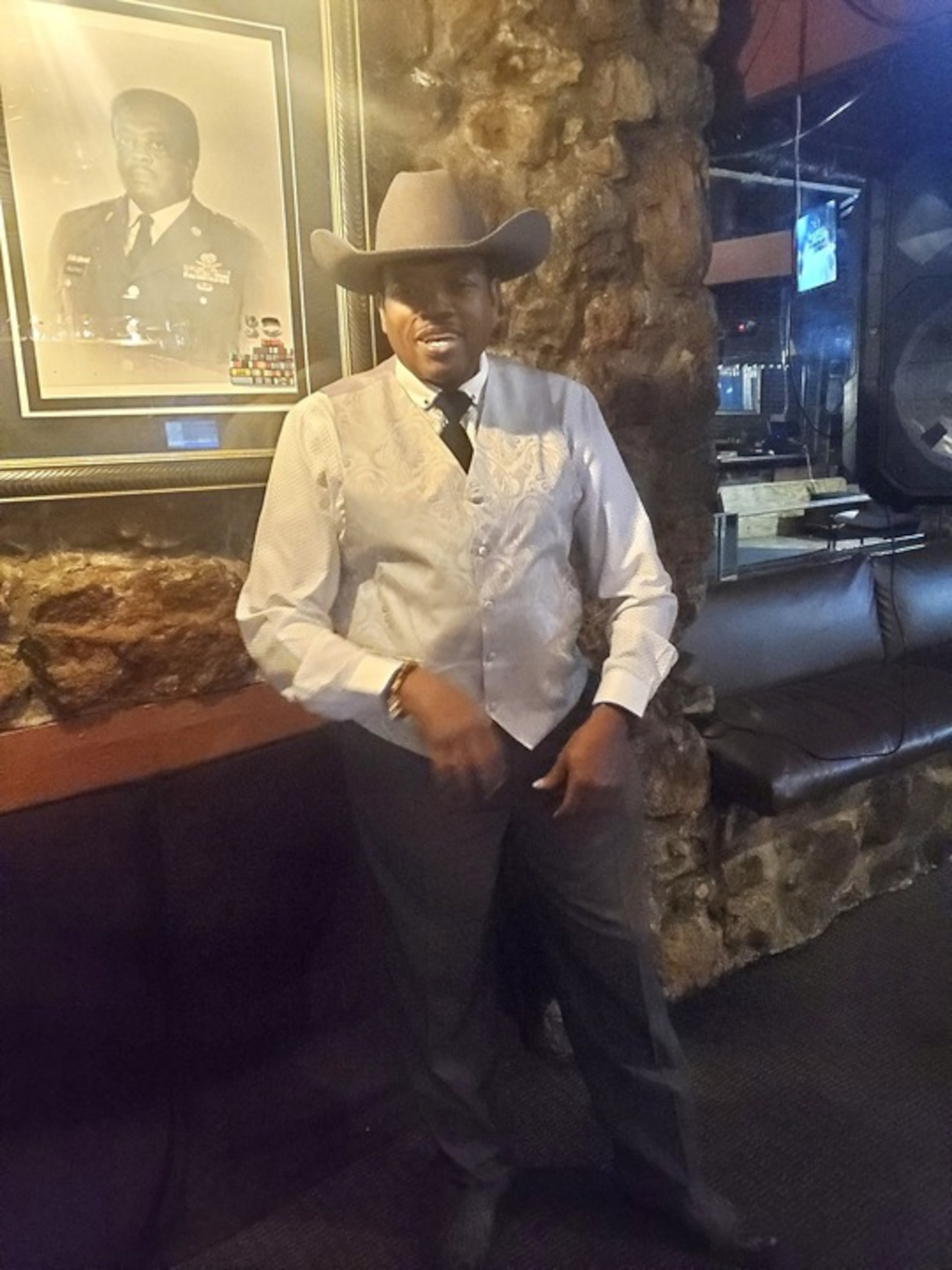 Ronnie Ogletree poses at Club 291 with a portrait of his father, who founded the club nearly 40 years ago.