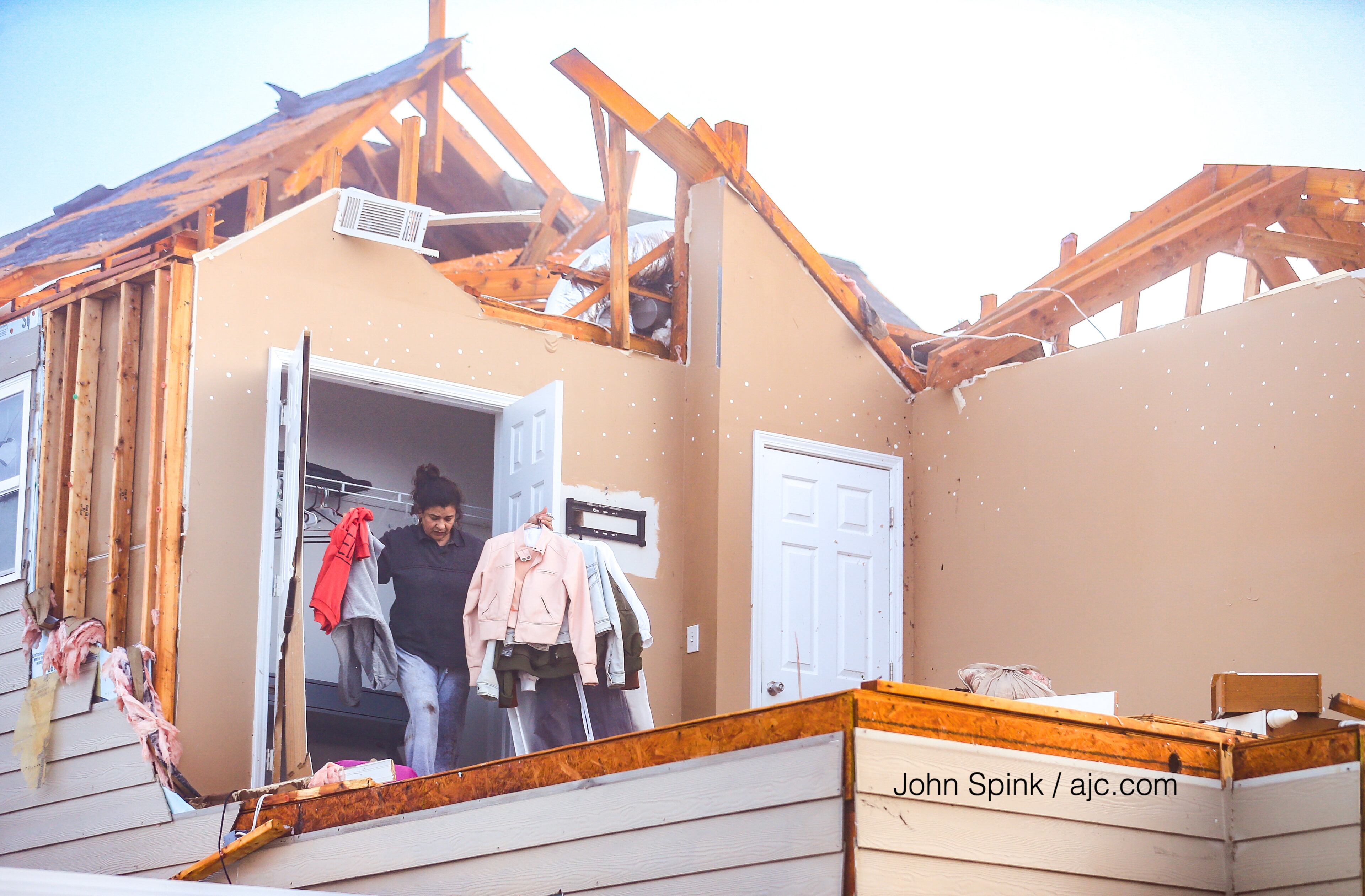 Marta Correa brings out her daughters clothing from the closet of her destroyed room in south Fulton County. JOHN SPINK / JSPINK@AJC.COM