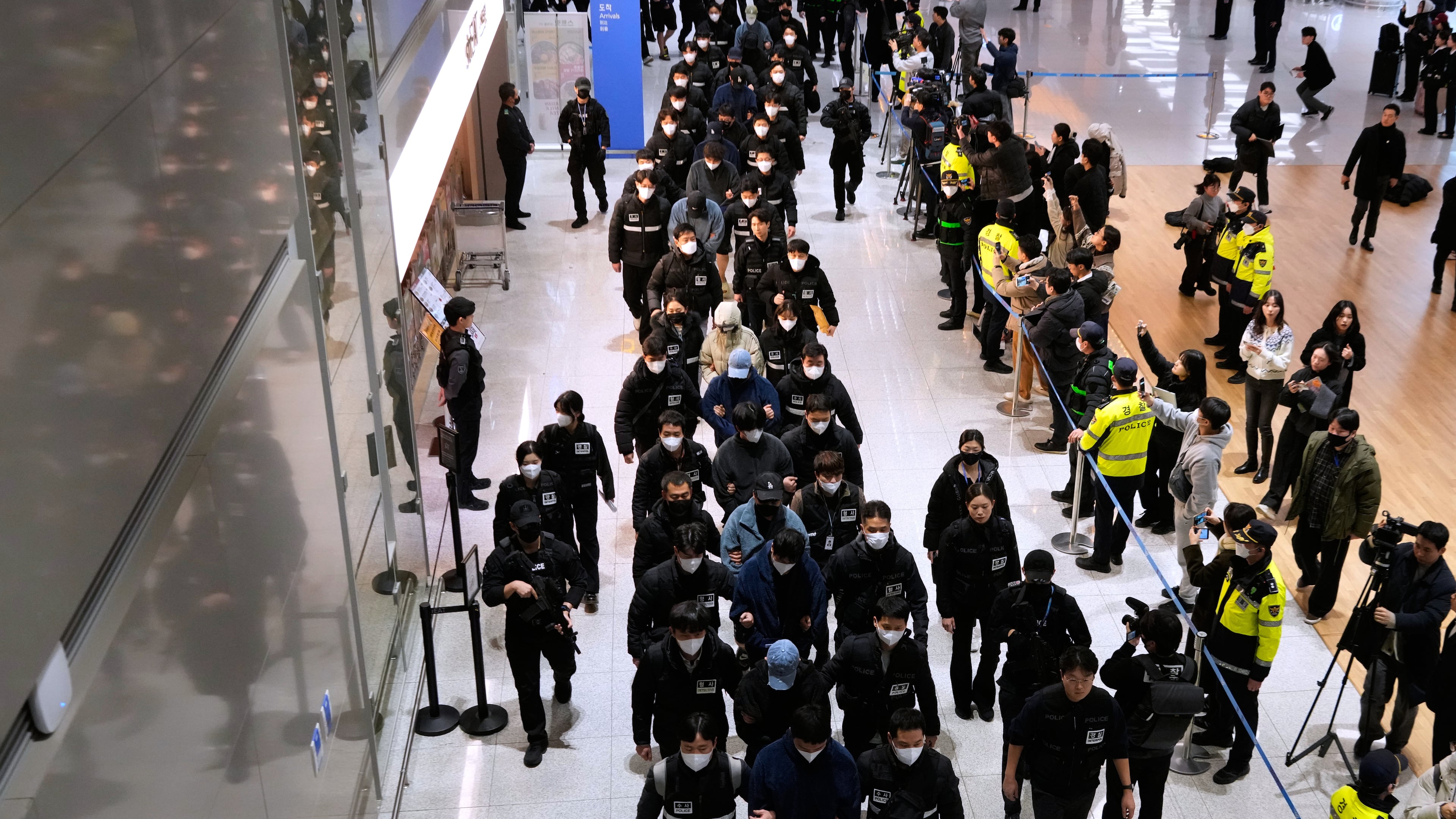 South Koreans, walking in the line at center, who are allegedly involved in online scams in Cambodia, arrive at the Incheon International Airport, in Incheon, South Korea, Friday, Jan. 23, 2026. (AP Photo/Ahn Young-joon)