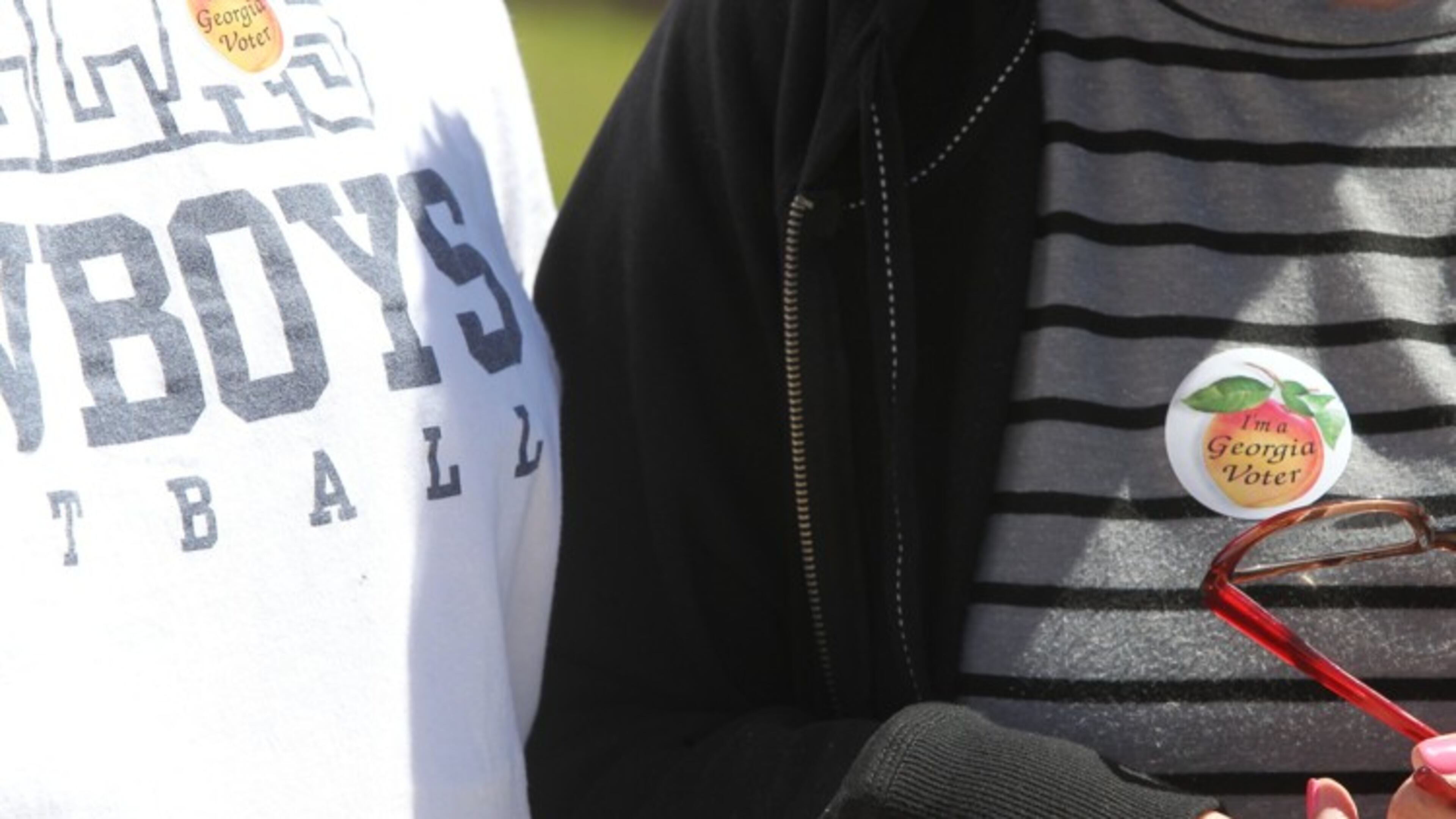 Voters brandish their Georgia voting stickers after leaving the Cobb County main elections office. Henry Taylor, henry.taylor@ajc.com