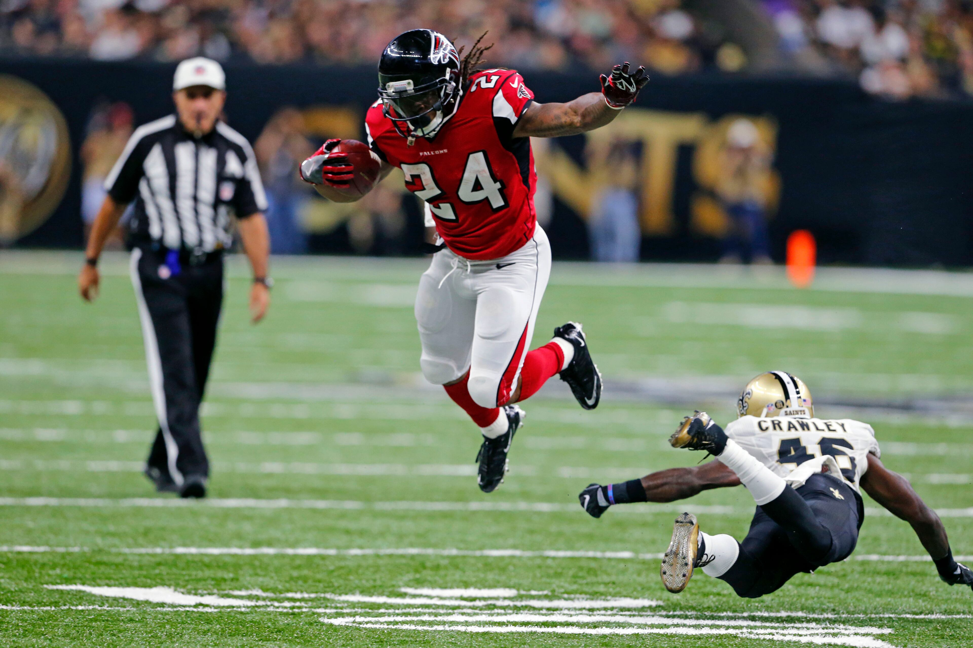 Atlanta Falcons running back Devonta Freeman (24) tries to avoid the tackle by New Orleans Saints cornerback Ken Crawley (46) in the first half of an NFL football game in New Orleans, Monday, Sept. 26, 2016. (AP Photo/Butch Dill)