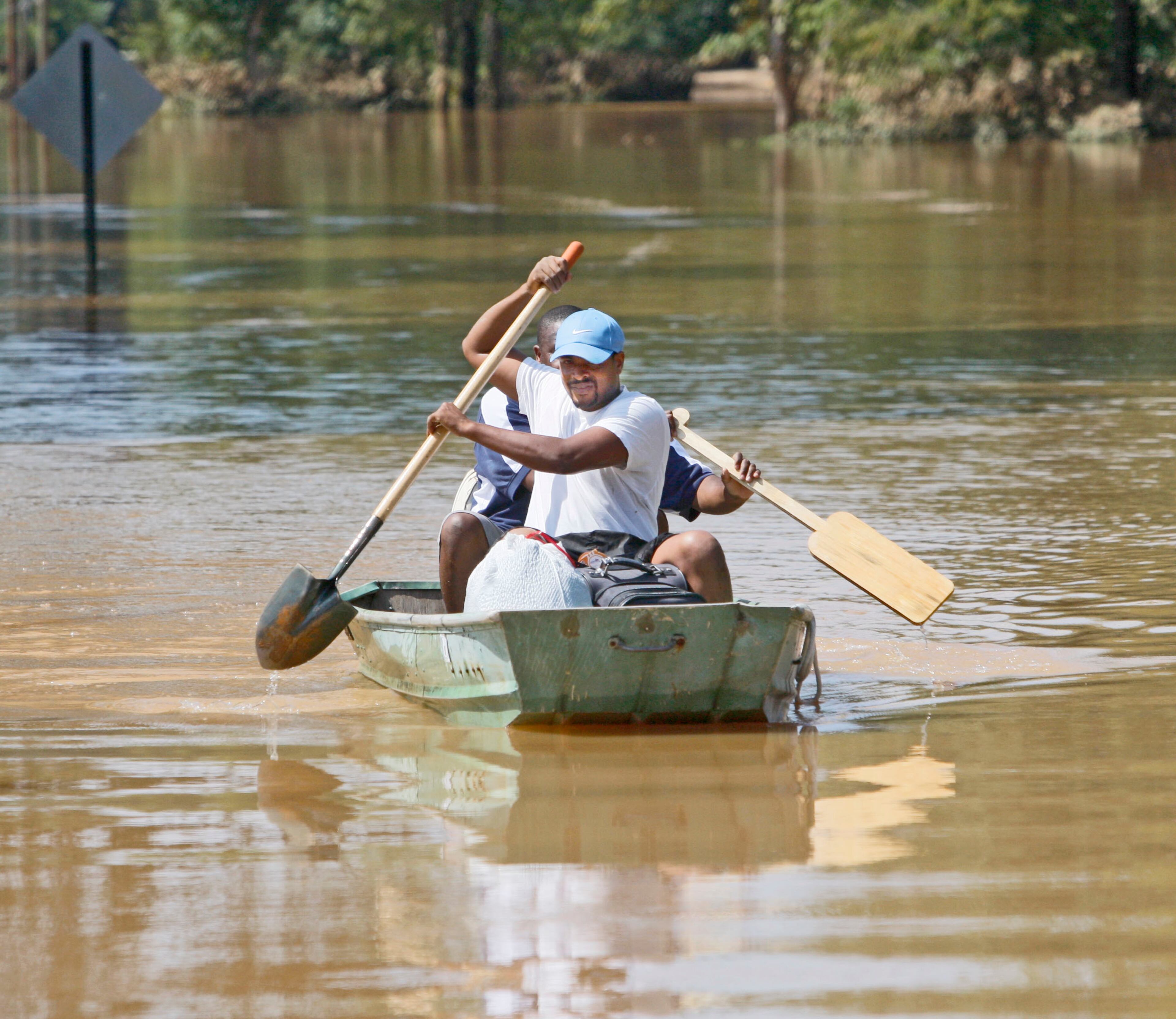 090922- Powder Springs - Earl Knight uses a shovel as an oar as rows down the still flooded Oglesby Road in Powder Springs with Cornell Daniels. Daniels home is flooded, and Knight is a friend from his church who was on hand to help him. Some roads remained closed and flooded in Powder Springs. The Five Oaks neighborhood remained inaccessible due to flood waters, but some residents attempted to get to their houses by boat, or by wading through the water. One house burned to the ground yesterday when Cobb County firefighters had to abandon their engine due to rising water. The house still smolders today. Tues Sep. 22, 2009. Bob Andres, bandres@ajc.com
