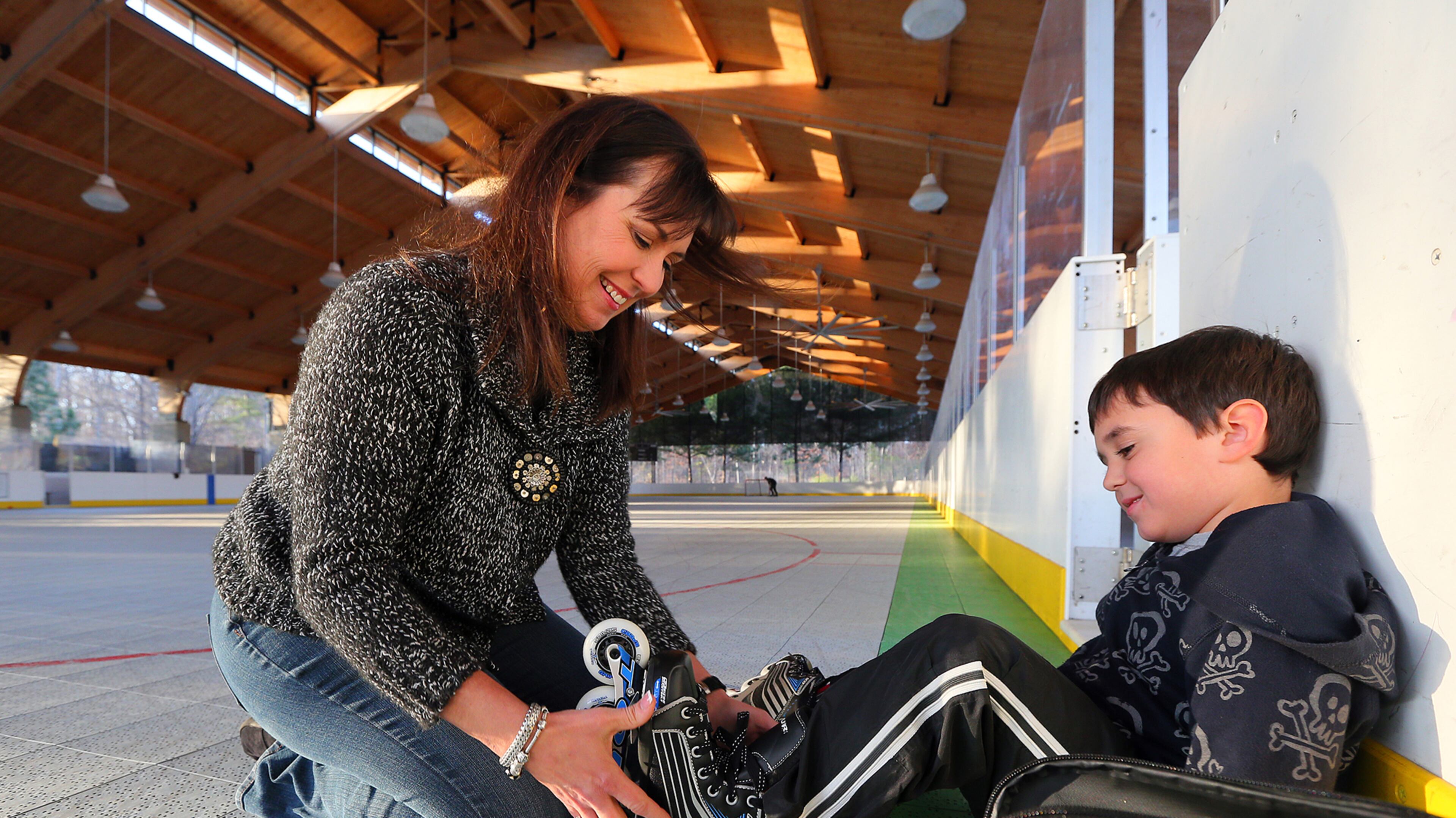 Wendy Pyles helps her son Hagan put on his skates at the roller hockey rink at Pinckneyville Park in Norcross in this 2013 file photo.