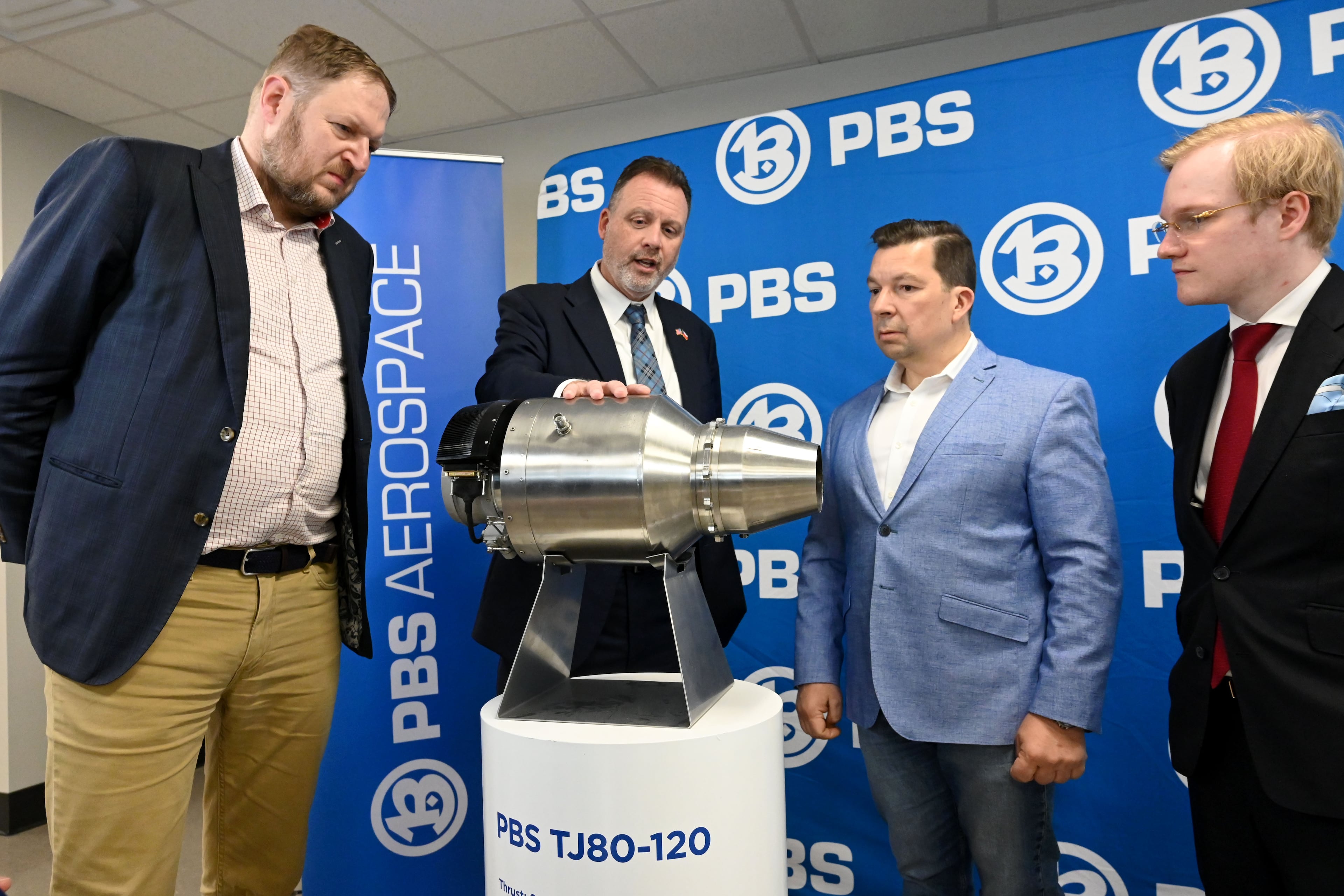 Erin Durham (second from left), CEO of PBS Aerospace, shows a PBS subsonic engine to (from left) David Müller, deputy minister of the Czech Ministry of Industry and Trade; Miloslav Stašek, Czech ambassador to the U.S.; and Jakub Fischer, managing director of PBS Aerospace on May 14, 2026, in Roswell. (Hyosub Shin/AJC)