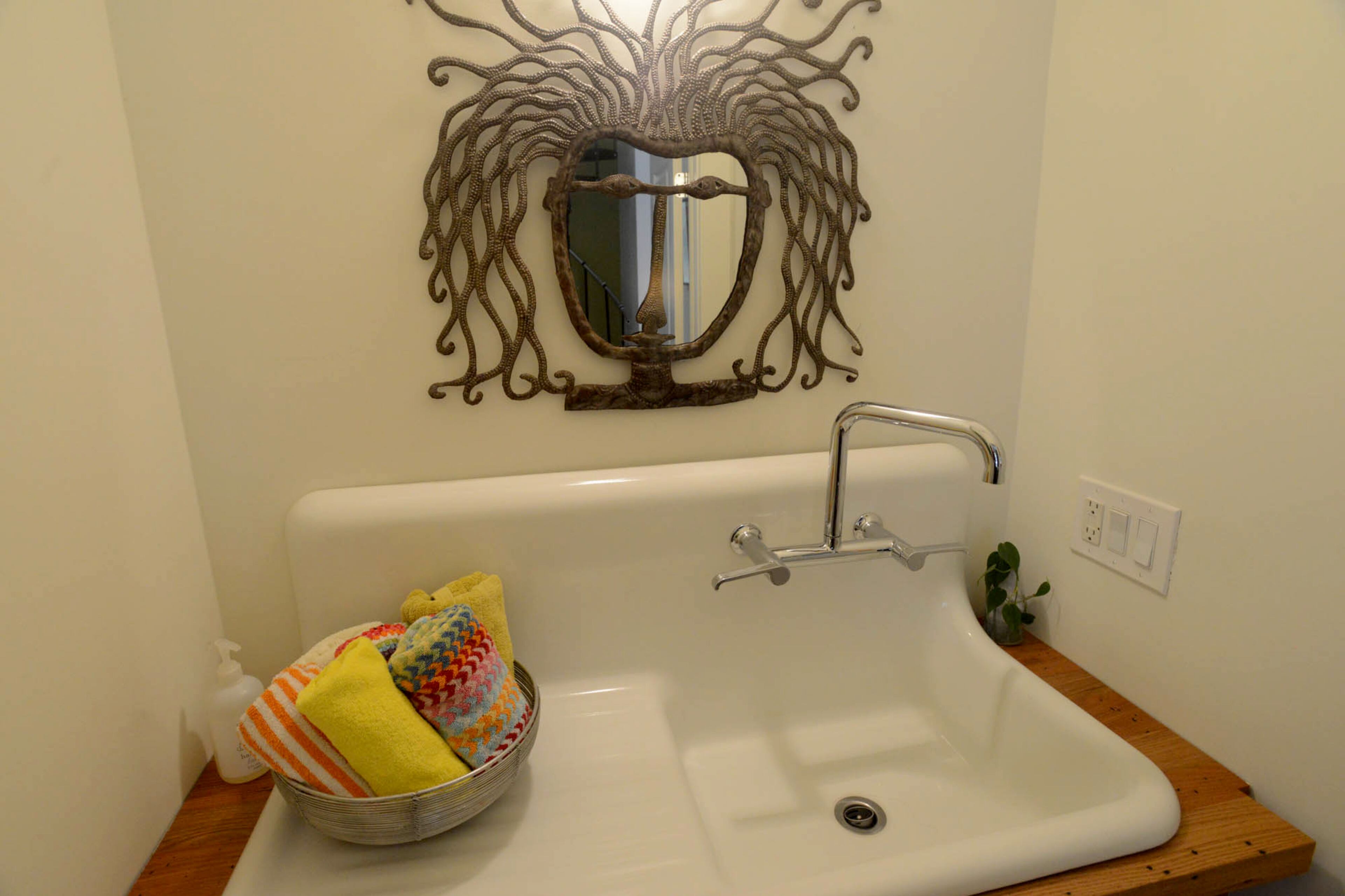 A whimsical face mirror looks back at visitors to Karen and Kirk Marchisen’s Atlanta home. The mirror came from an art festival. The sink and bathroom fixtures are by Kohler.