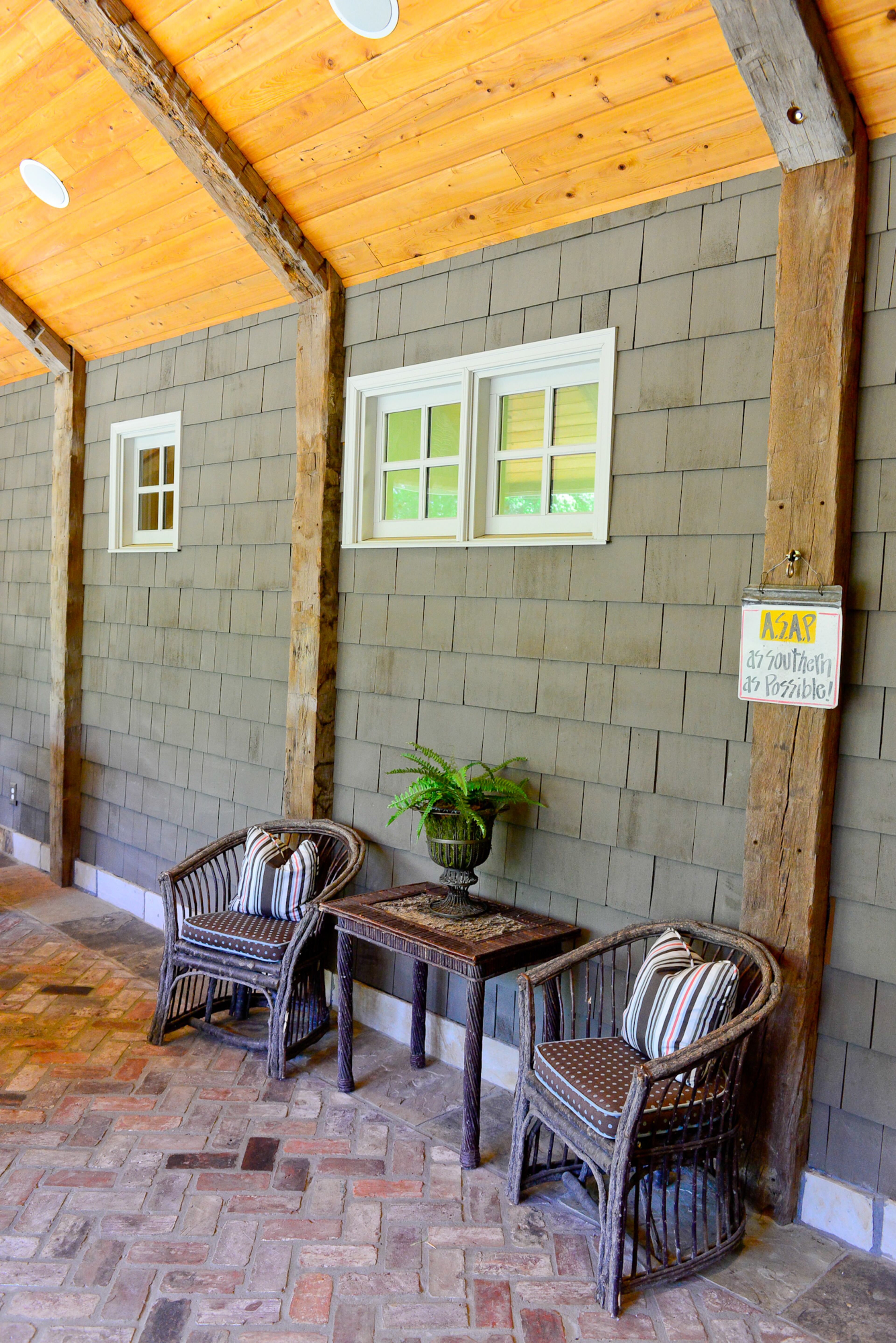 Twig chairs, purchased at Lake Rabun, create a rustic nook on the screened porch. The beams are from a barn in Ohio that was built in 1820.