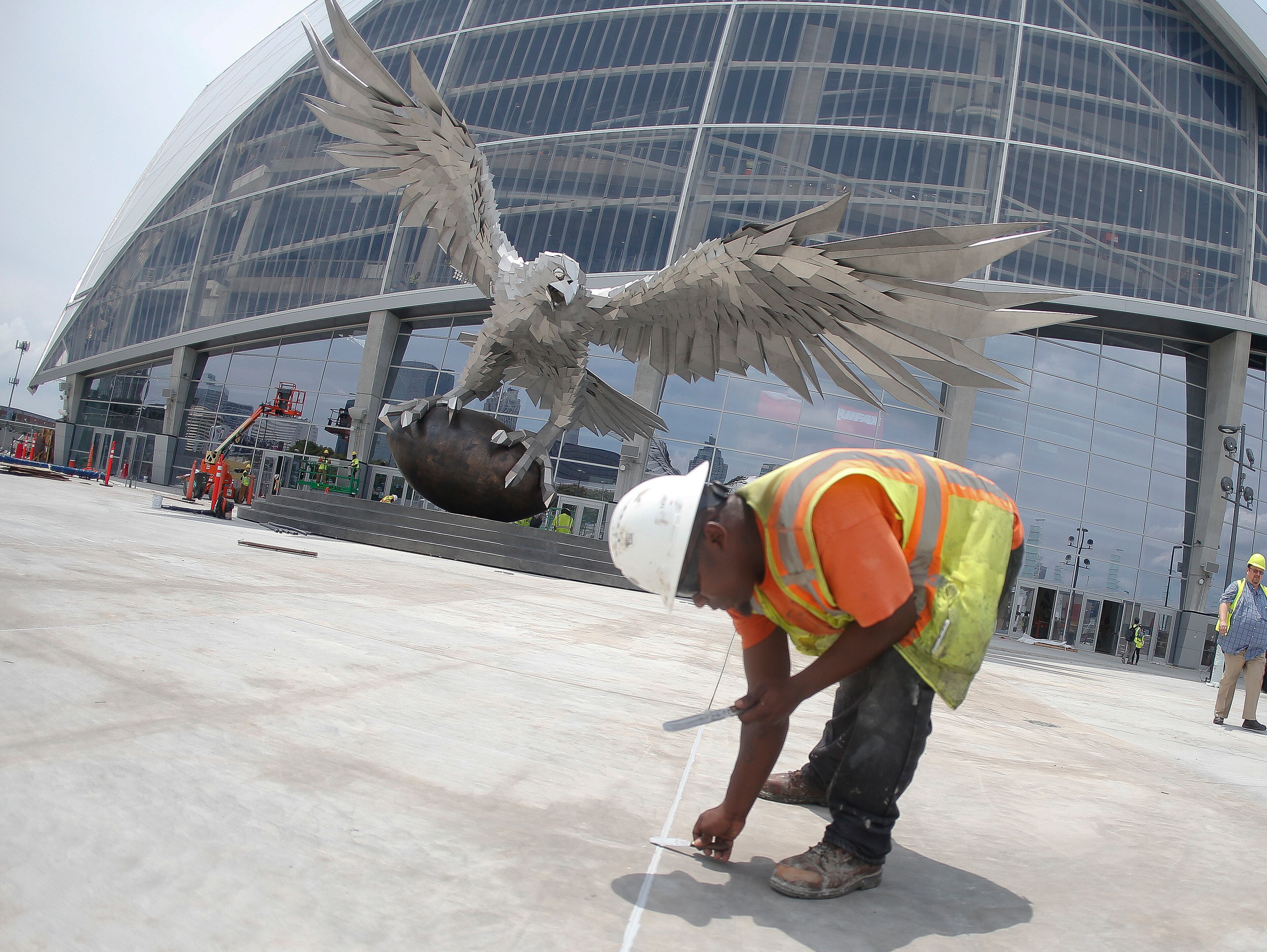 A worker fills cracks in the pavement outside the entrance to the Mercedes Benz Stadium, new home of the Atlanta Falcons football team and the Atlanta United soccer team, Tuesday, July 25, 2017, in Atlanta. (AP Photo/John Bazemore)
