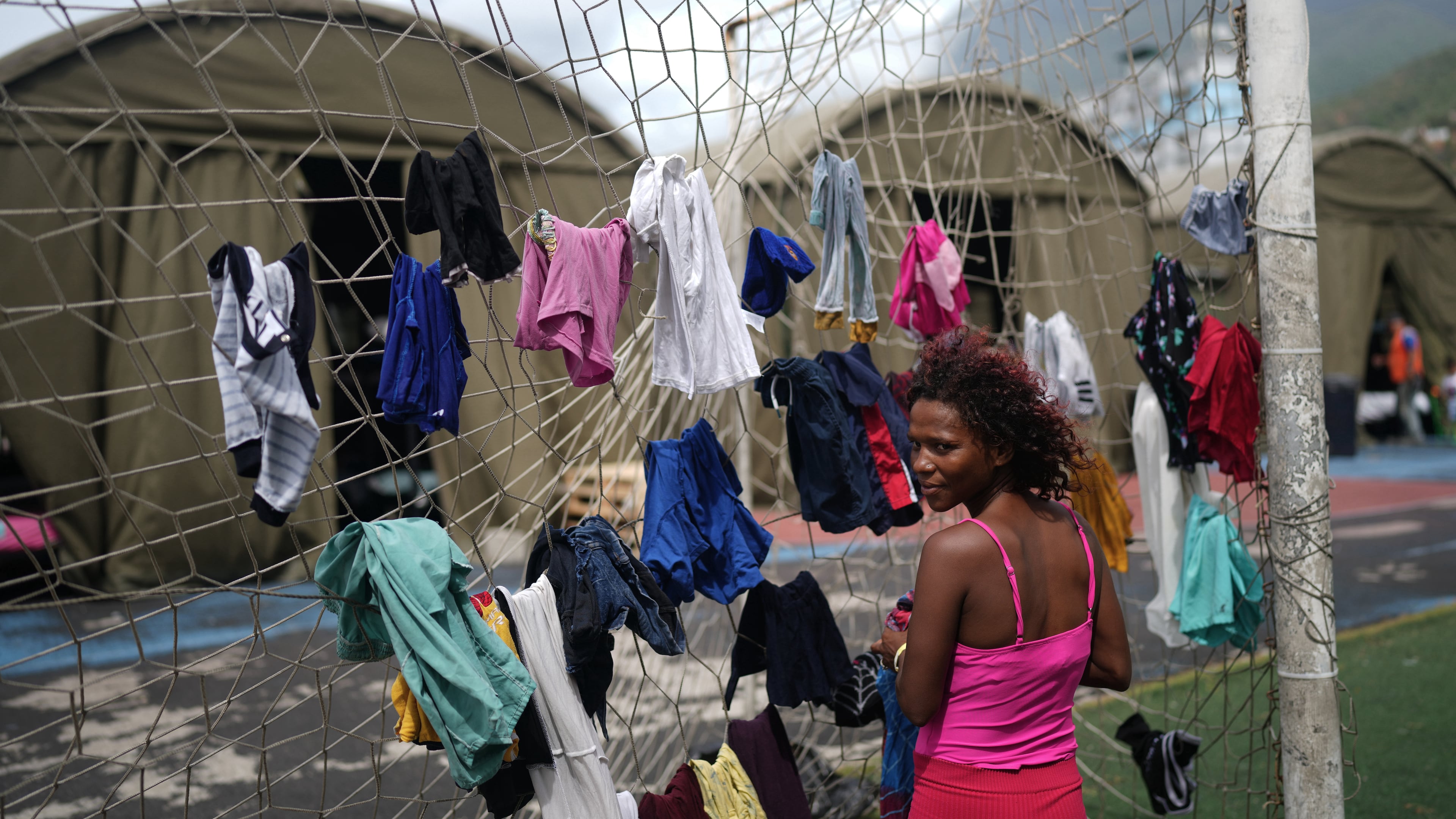 Nataly Mayora hangs clothes to dry on a soccer goal net as she does laundry at a sports center sheltering people displaced by the earthquakes in La Guaira, Venezuela, Thursday, July 9, 2026. (AP Photo/Ariana Cubillos)