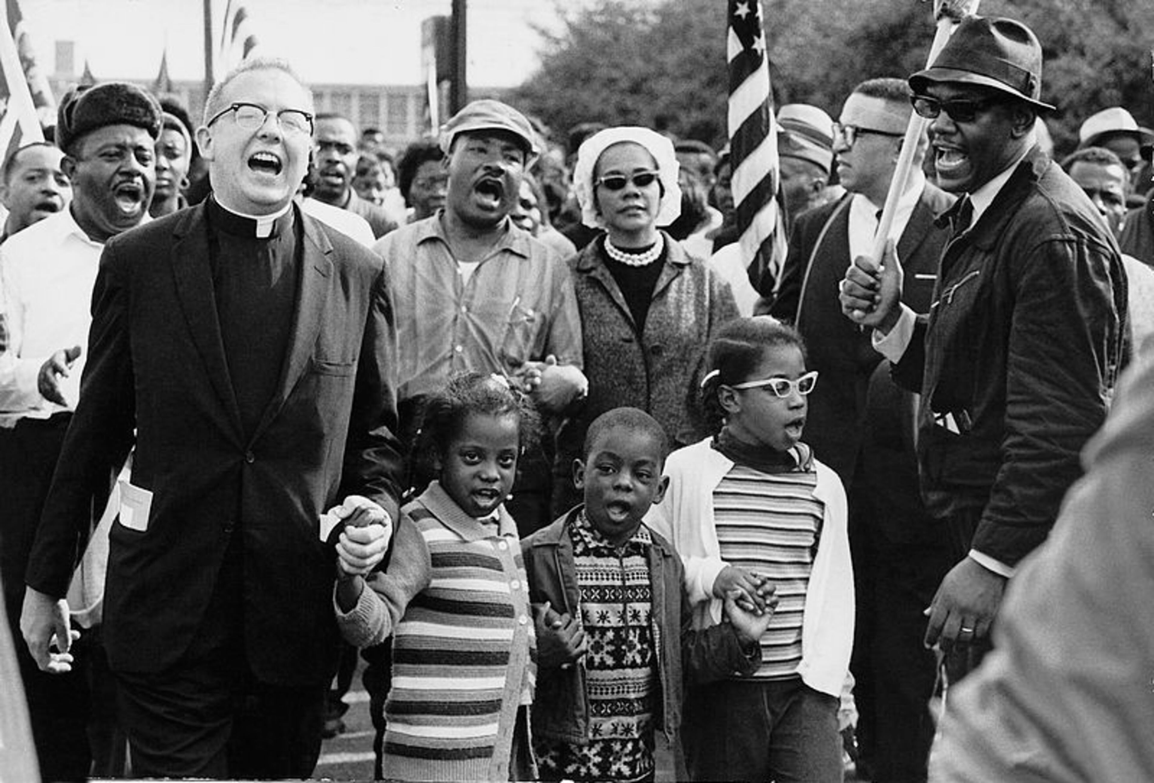 Civil Rights Movement Co-Founder Dr. Ralph David Abernathy and his wife Mrs. Juanita Abernathy follow with Dr. and Mrs. Martin Luther King as the Abernathy children march on the front line, leading the SELMA TO MONTGOMERY MARCH in 1965. The Children are Donzaleigh Abernathy in striped sweater, Ralph David Abernathy, 3rd and Juandalynn R. Abernathy in glasses. Name of the white Minister in the photo is unknown.