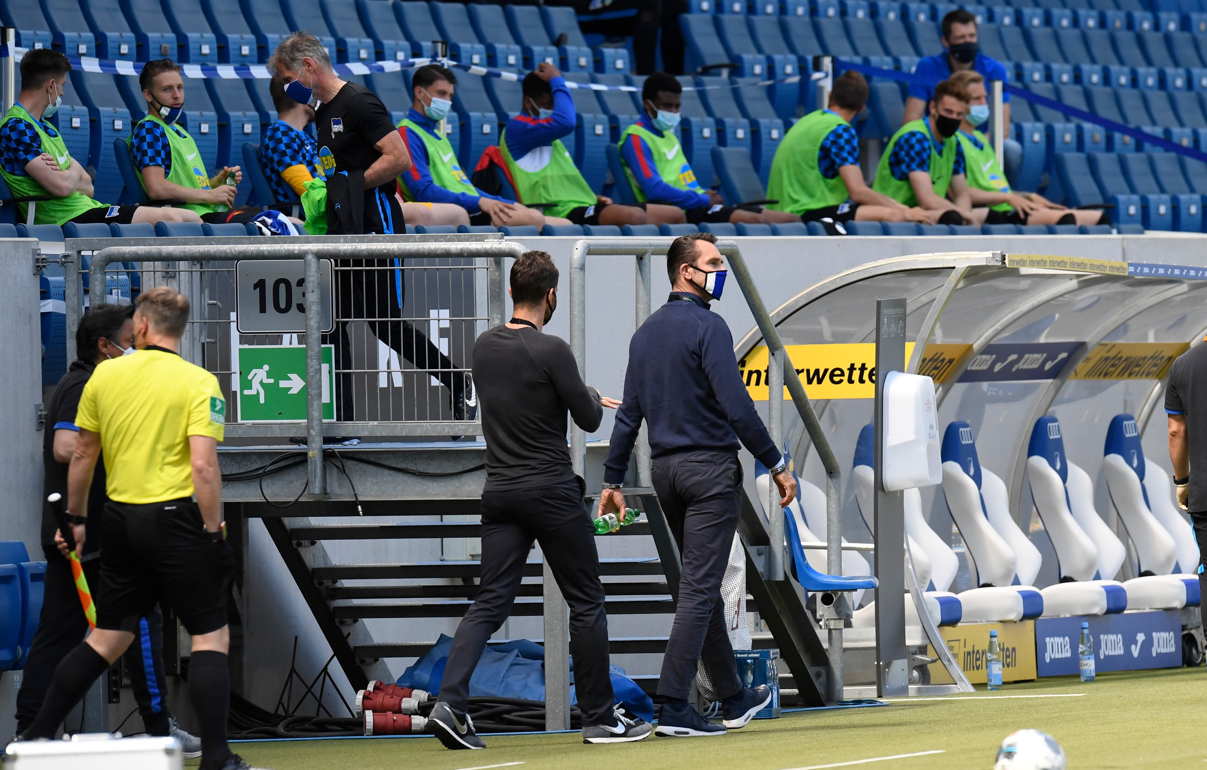 Hertha's manager Michael Preetz wears a face mask as he enters the stadium while Hertha's substitution players sit on the stands to keep the distance prior to the Bundesliga soccer match between TSG 1899 Hoffenheim and Hertha BSC Berlin in Sinsheim, Germany, Saturday, May 16, 2020. The German Bundesliga becomes the world's first major soccer league to resume after a two-month suspension because of the coronavirus pandemic. (Thomas Kienzle/AFP pool via AP)