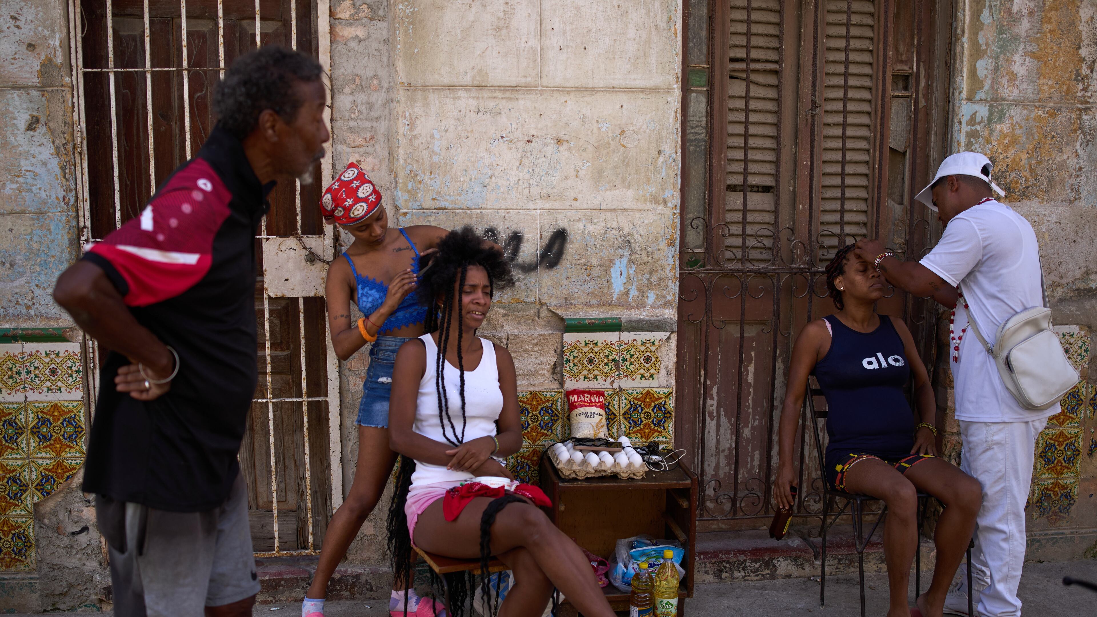 Hairdressers style the hair of their clients in the open air during a blackout in Havana, Cuba, Thursday, March 5, 2026. (AP Photo/Ramon Espinosa)