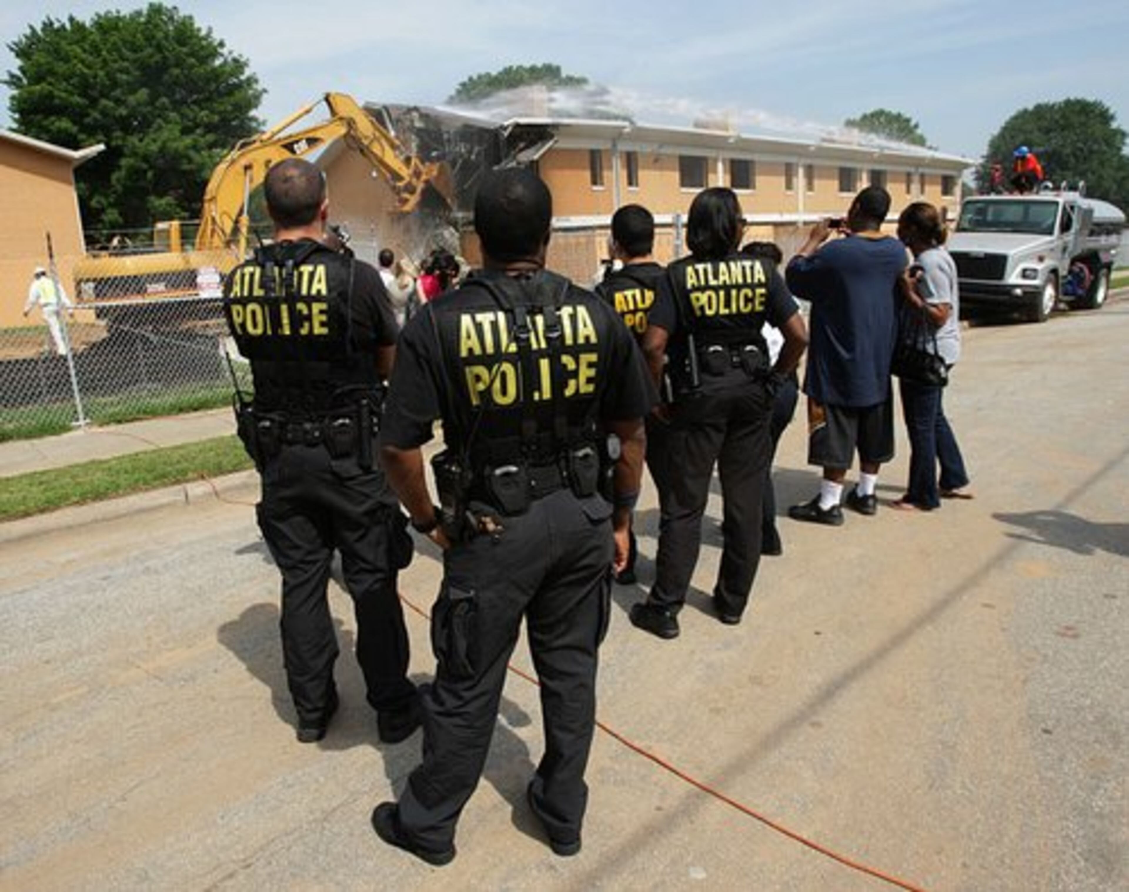 Atlanta Police Department officers watch the demolition of one of the apartments inside Bowen Homes.