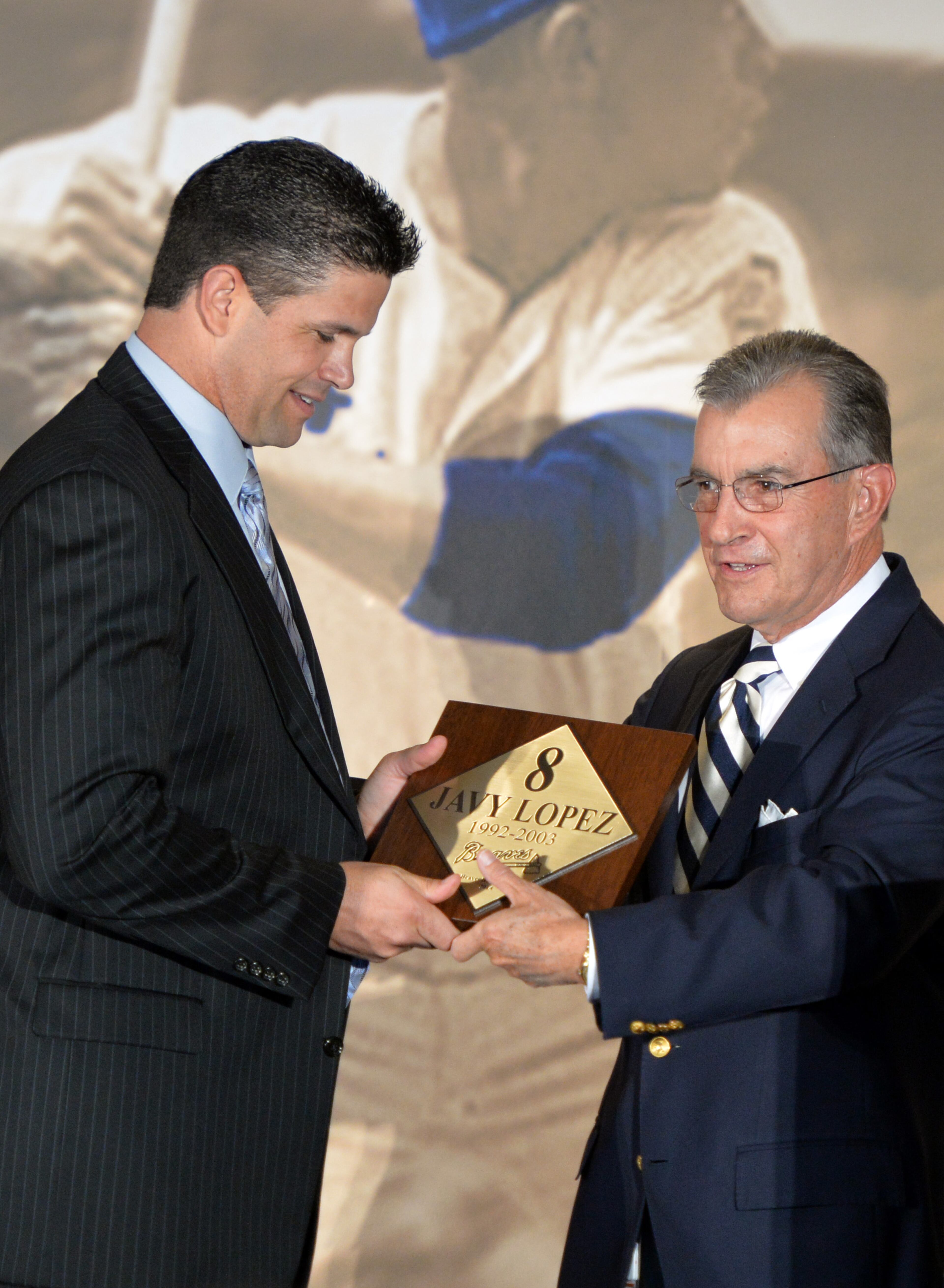 Braves president John Schuerholz presents a plaque to Lopez.