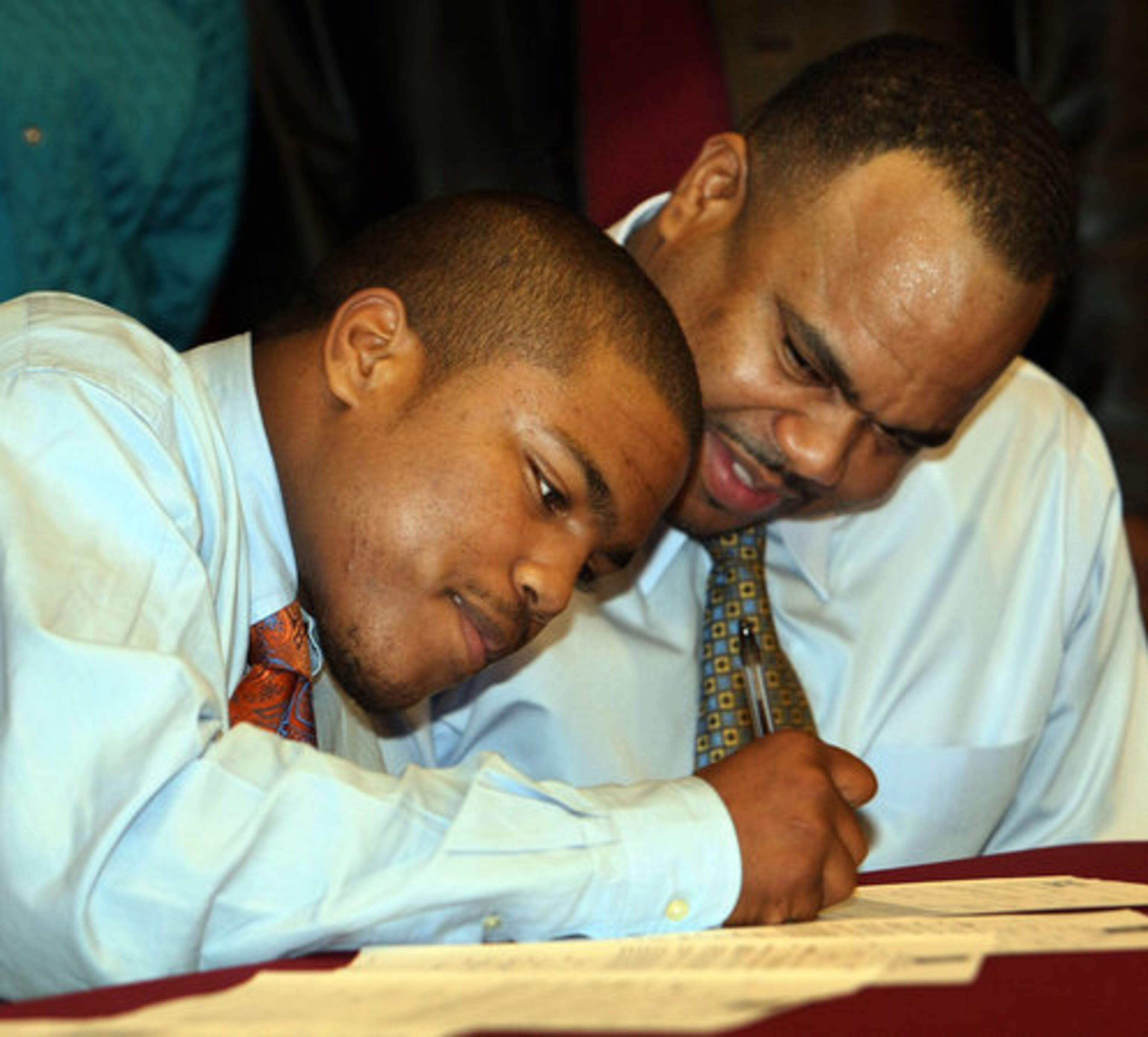 Broderick Sellers(left) is watched closely by his father Victor as he signs a letter of intent to play football at Savannah State during a ceremony at South Paulding High School on Wednesday, February 3rd.