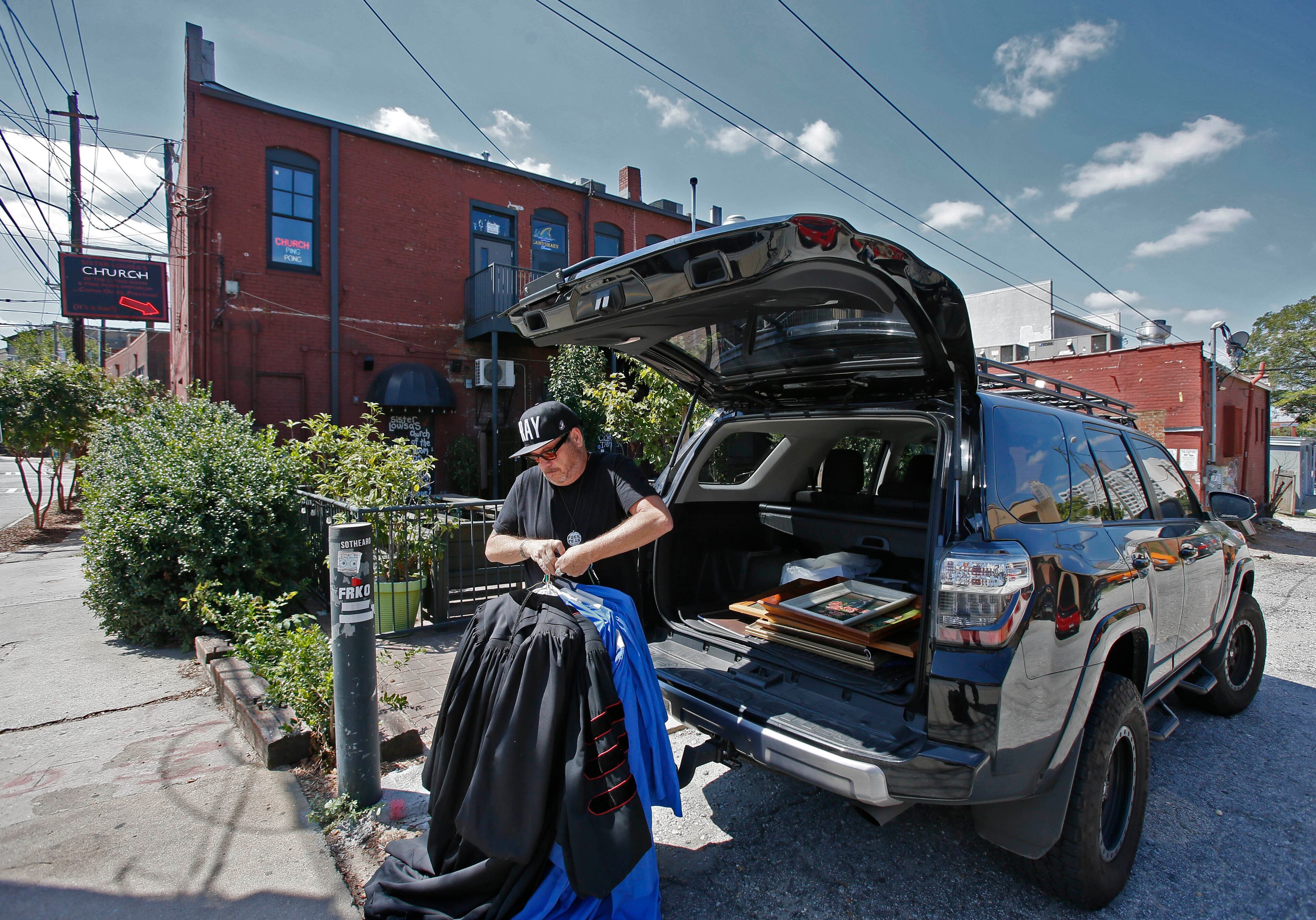 Grant unloads choir robes and old religious paintings from his vehicle parked in the alley behind Church in Atlanta. BOB ANDRES / BANDRES@AJC.COM