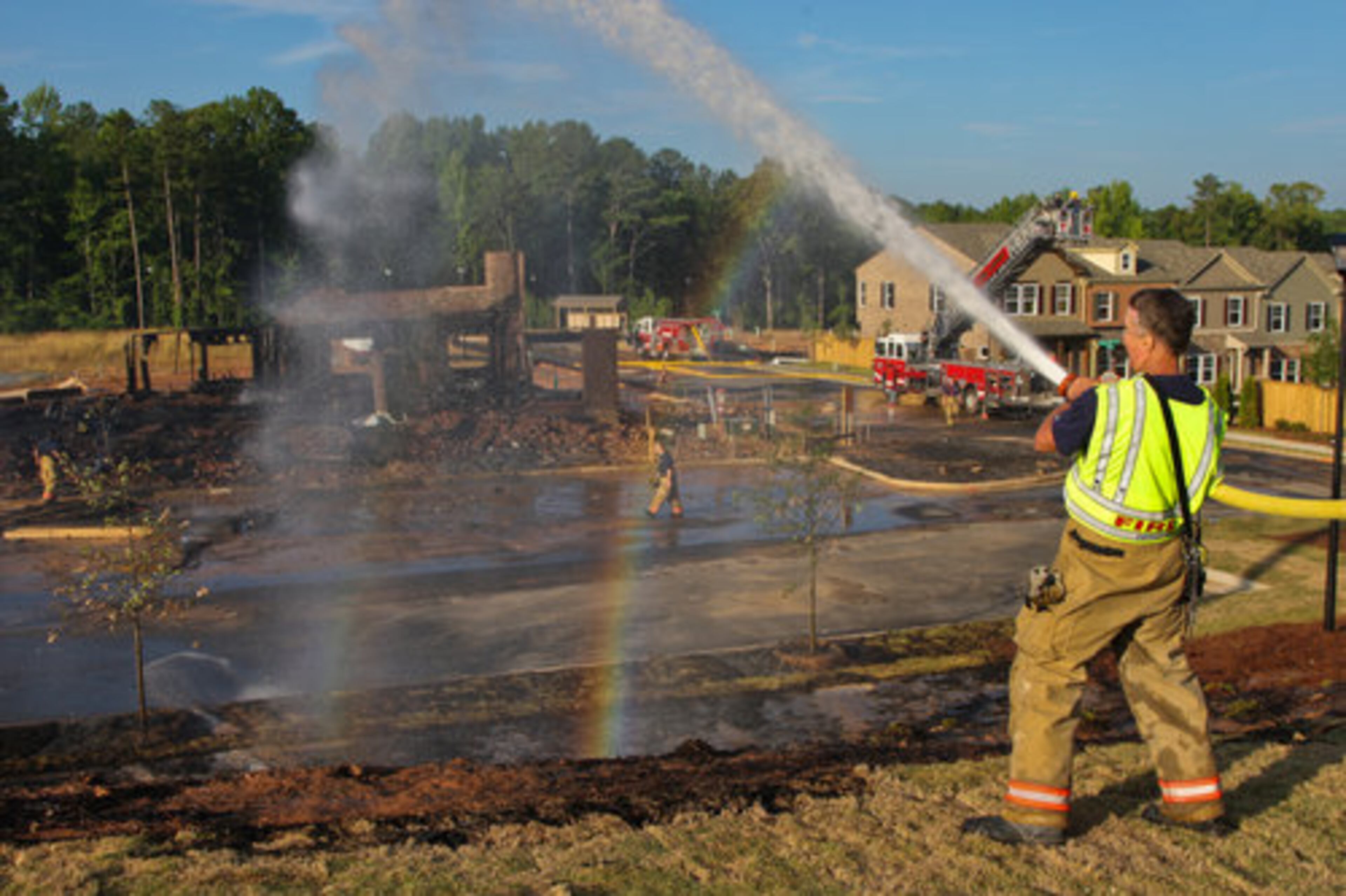 A rainbow forms under Cobb County firefighter Bill Dean as he douses additional flames that spread along the hillside of an Acworth office park fire on Friday morning. Morning rush commuters were delayed when Highway 19/41 was closed because of the blaze.